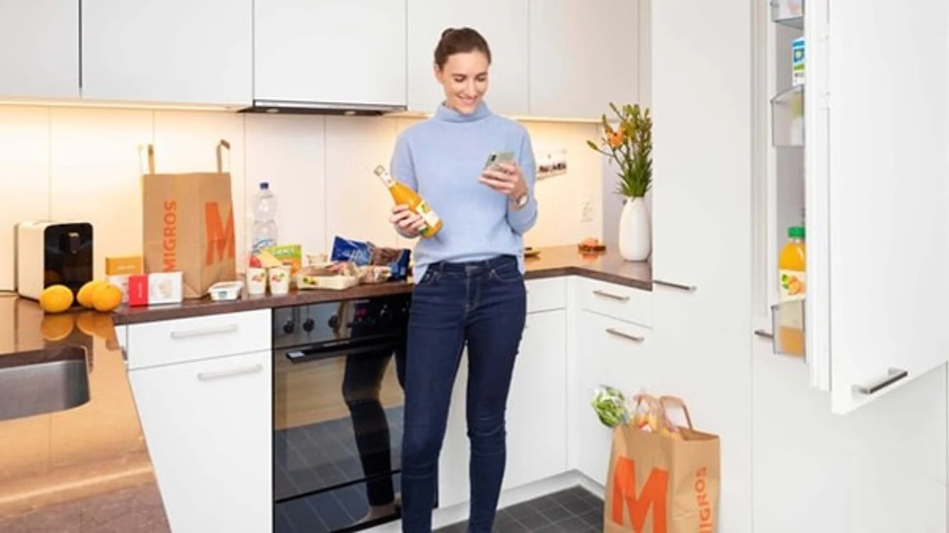 Eine Frau steht in der Küche und packt Einkäufe in den Kühlschrank