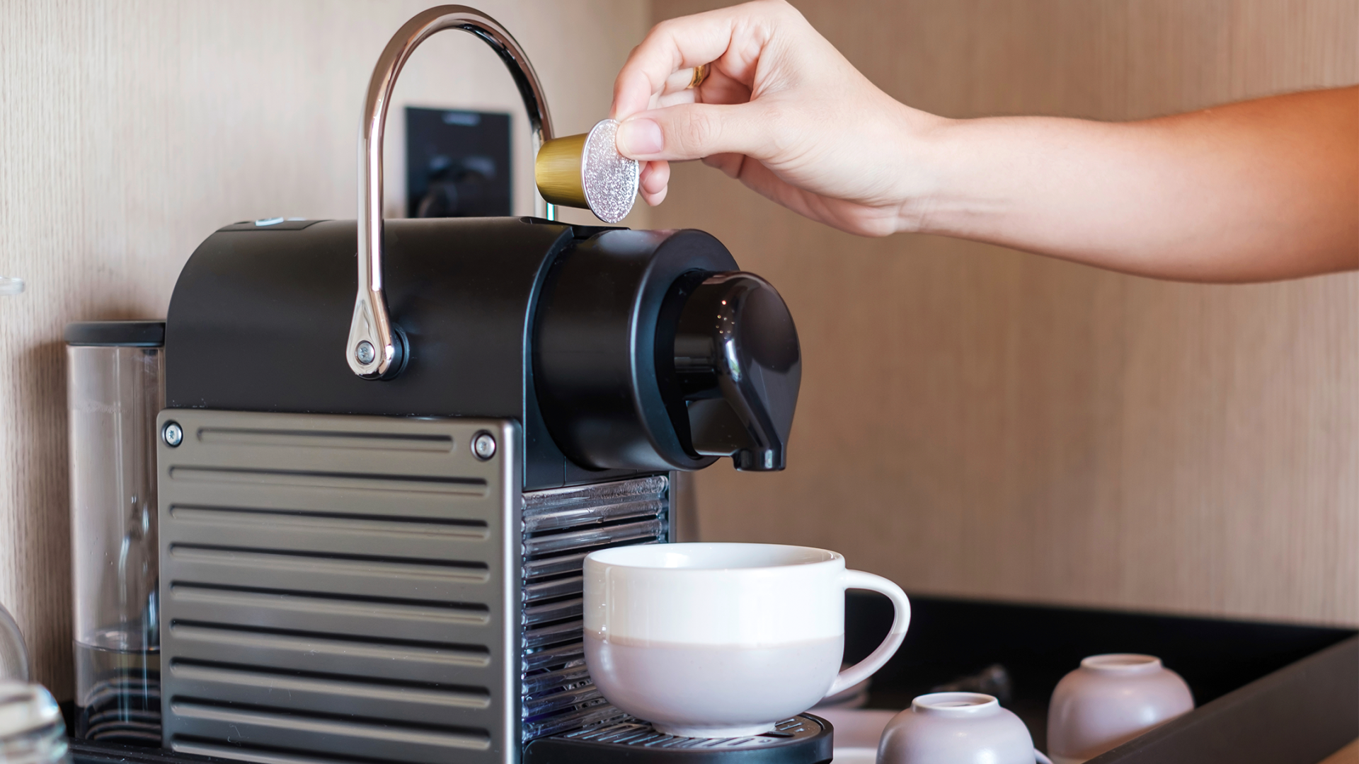 Eine Hand legt eine Kaffeekapsel in eine Kaffeemaschine