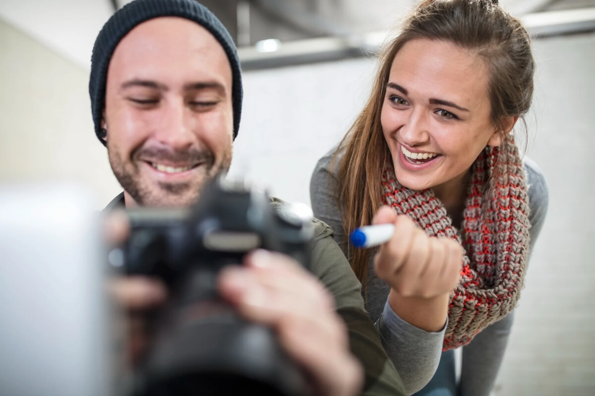 Two photographers look at a camera.