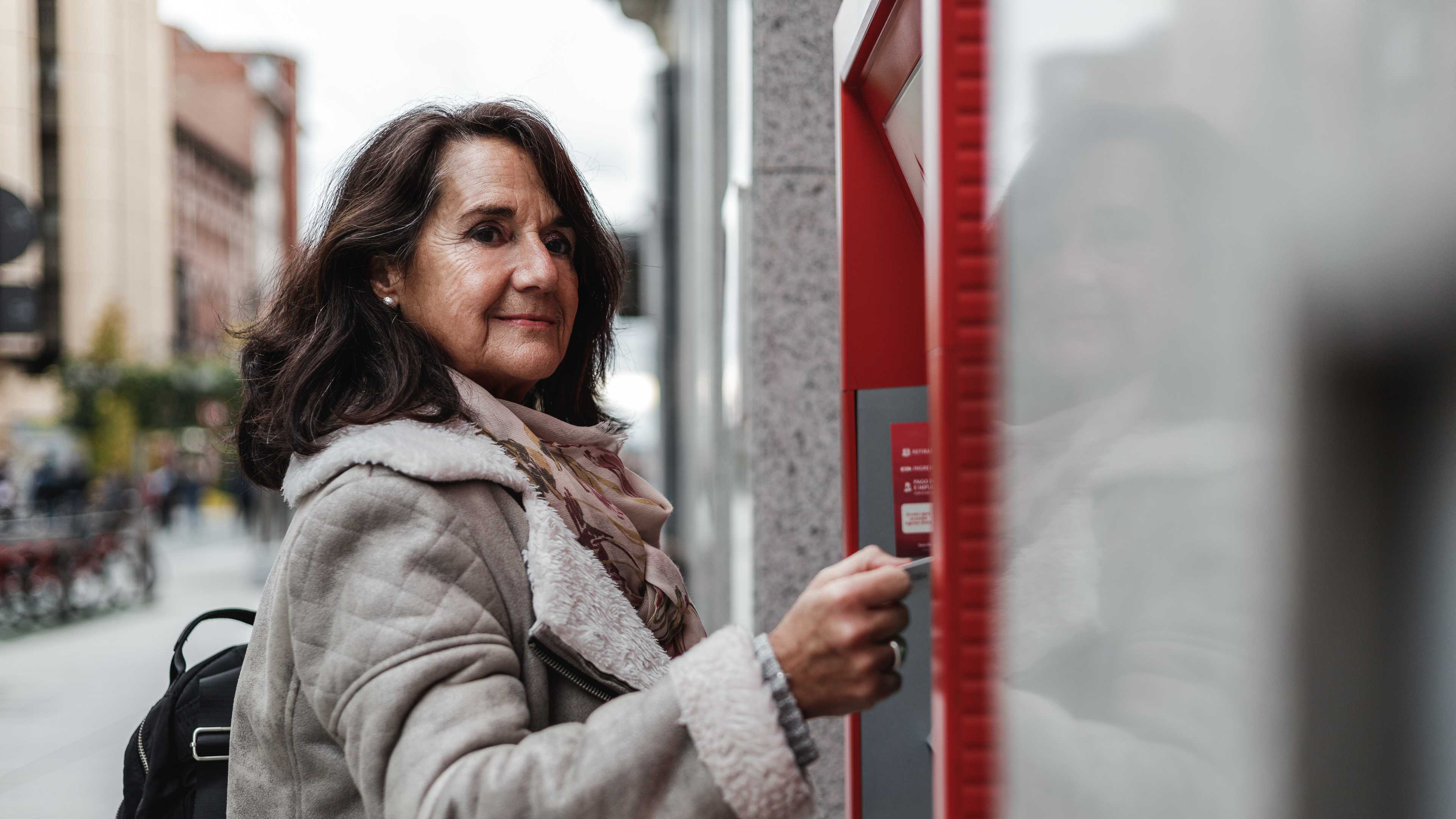 Una donna preleva denaro da un bancomat