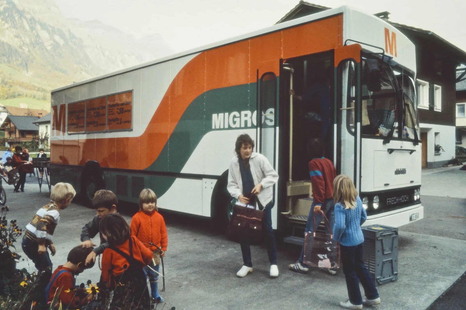 Kinder spielen und warten vor dem Migros Verkaufswagen