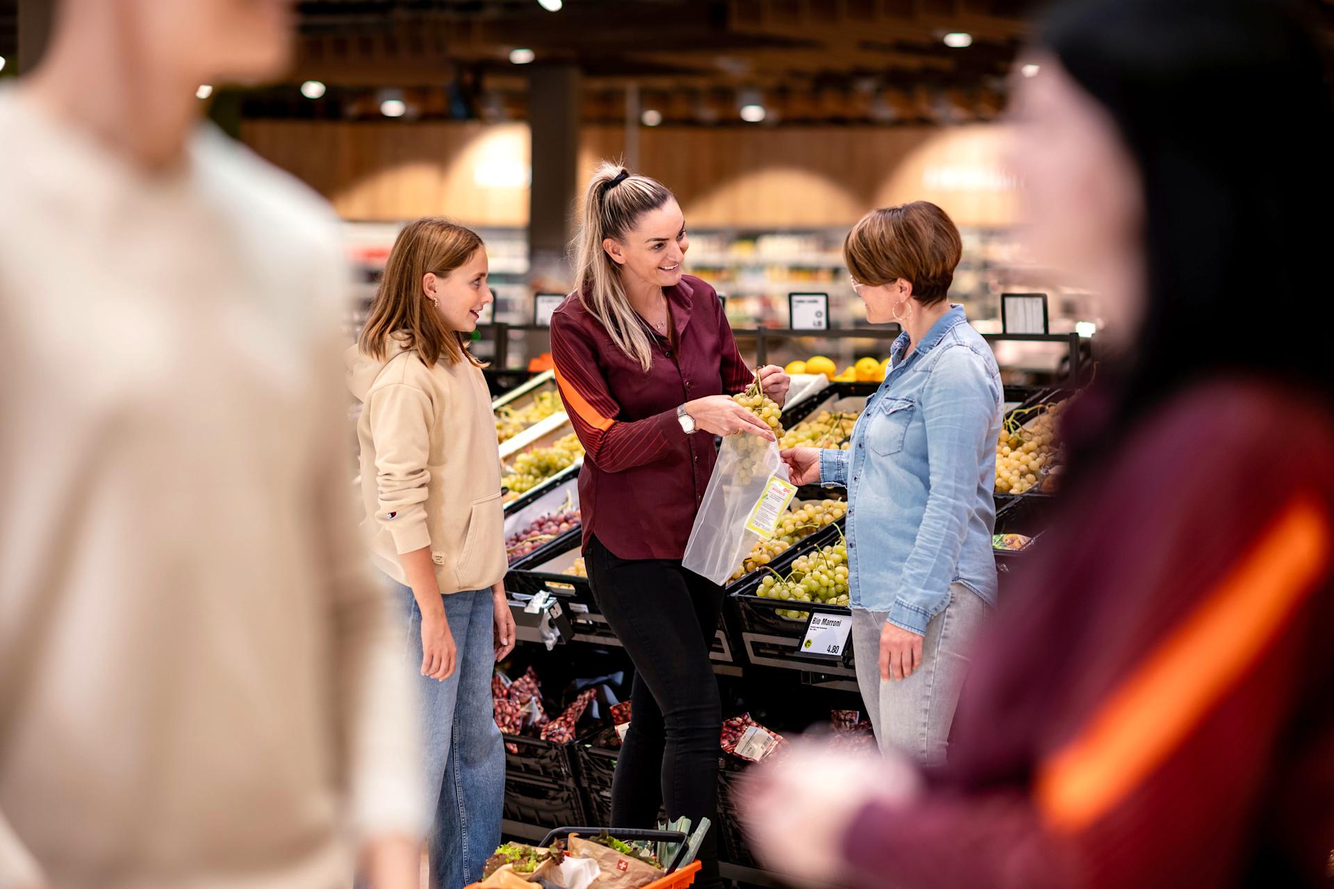 Une collaboratrice Migros aide une cliente à choisir des fruits