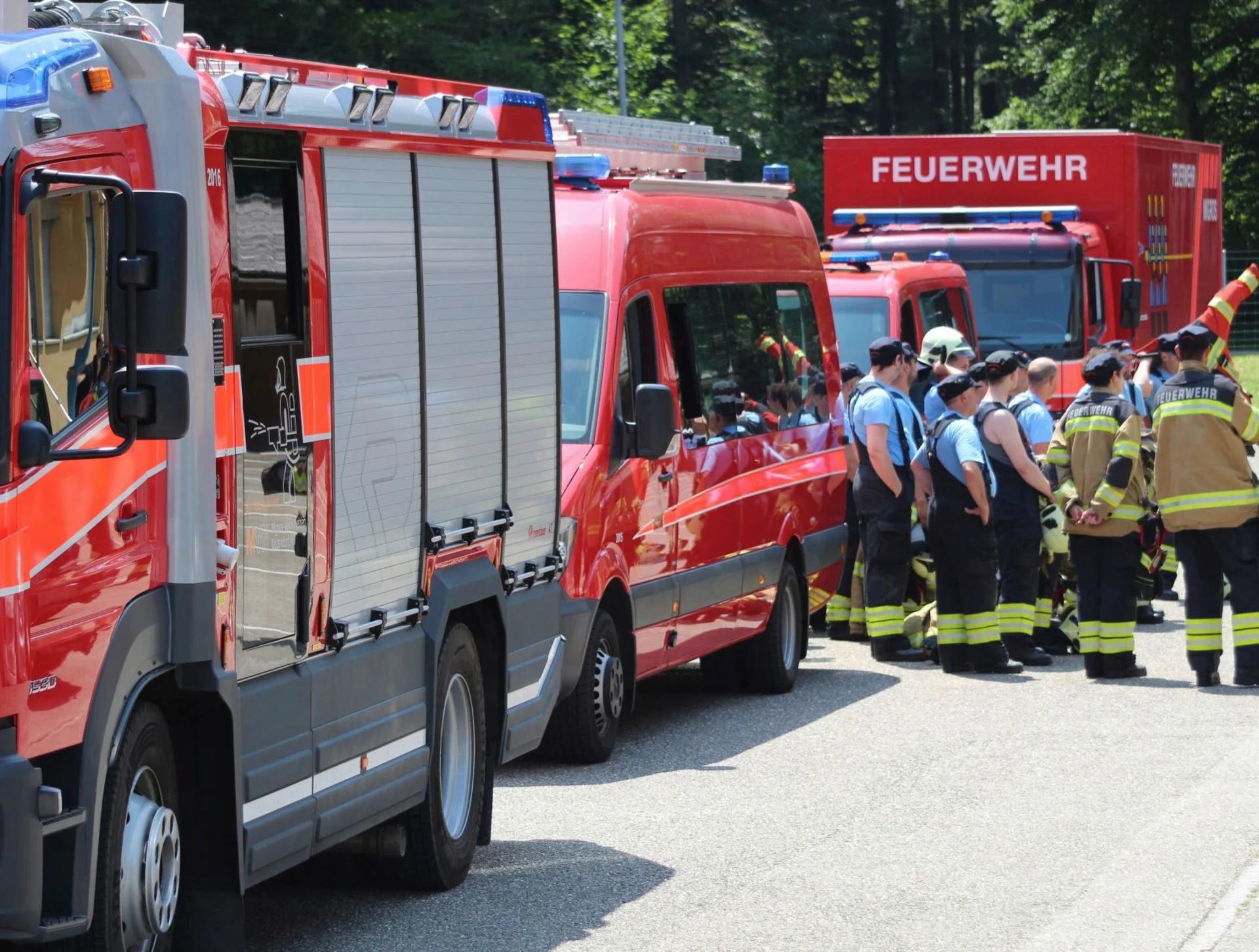 Trois véhicules de pompiers et un groupe de sapeurs-pompiers.