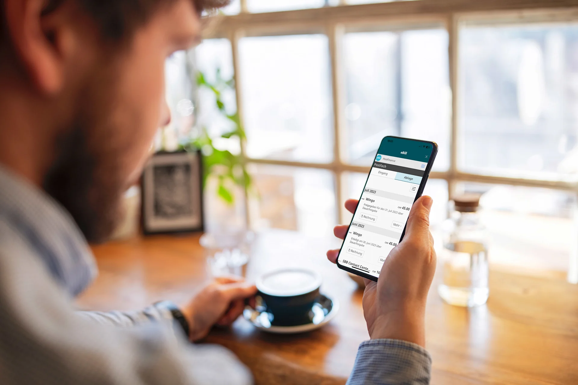 Ein Mann schaut in sein Handy und überprüft da seine Finanzen.