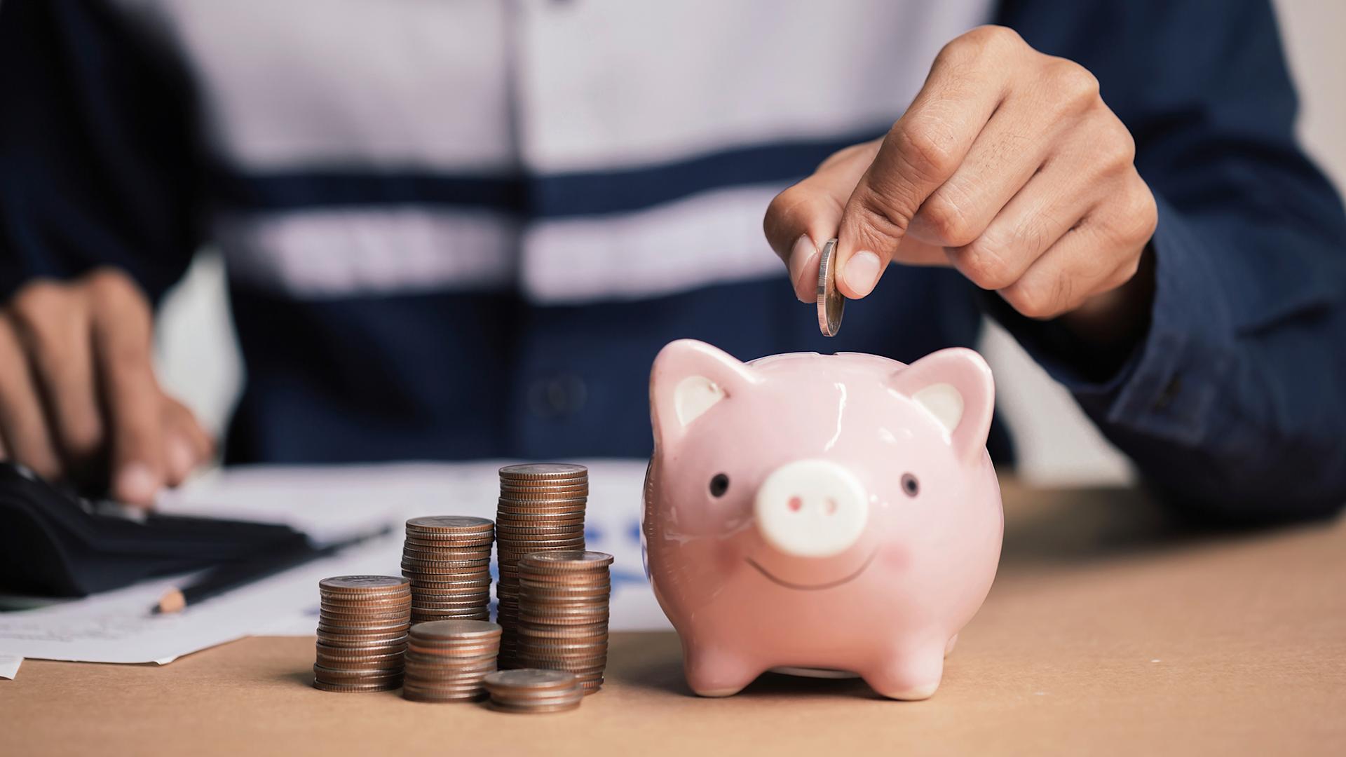 Pile de monnaie à côté d'une tirelire