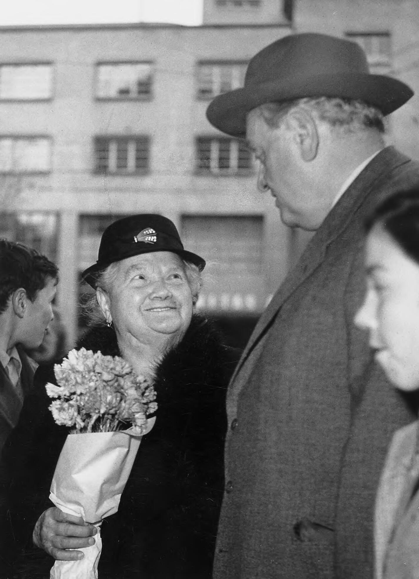 A black-and-white photograph of a woman holding flowers and looking up gratefully at Gottlieb Duttweiler