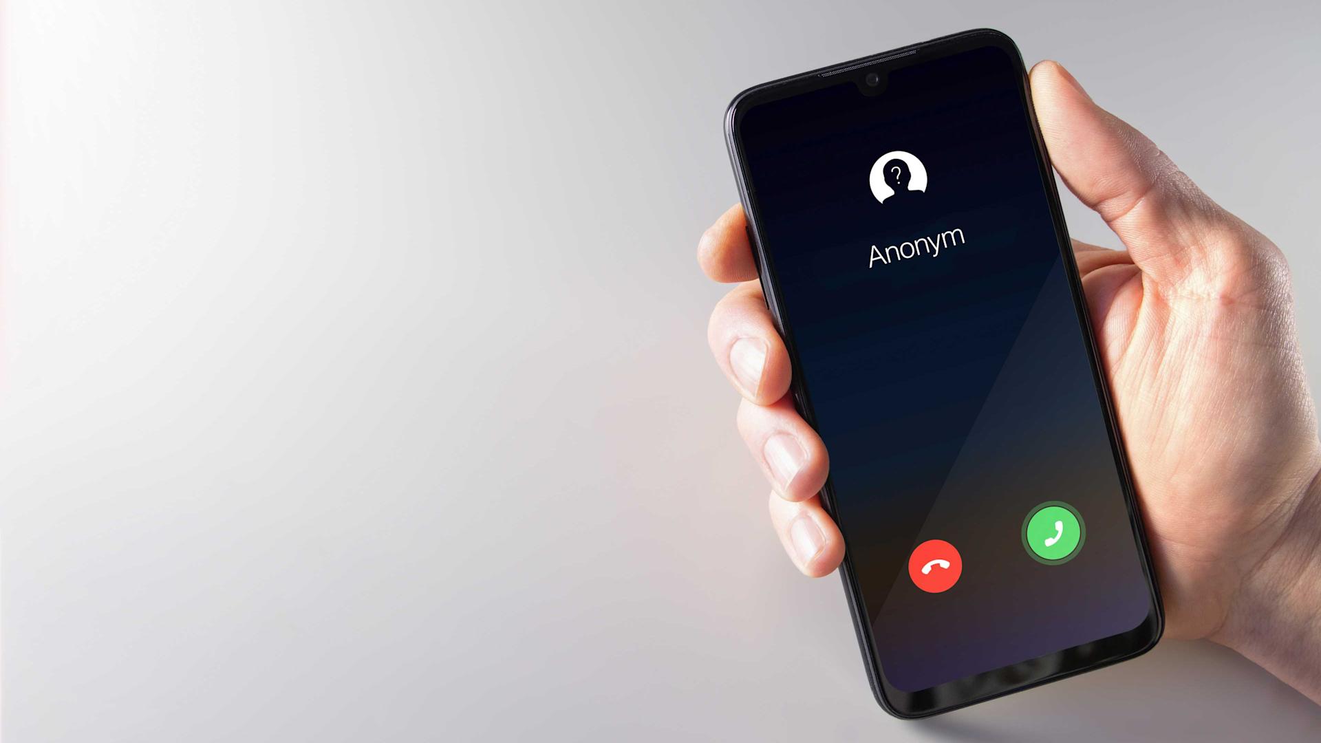 Männliche Hand hält ein Smartphone mit unbekanntem Anrufer auf dem Bildschirm