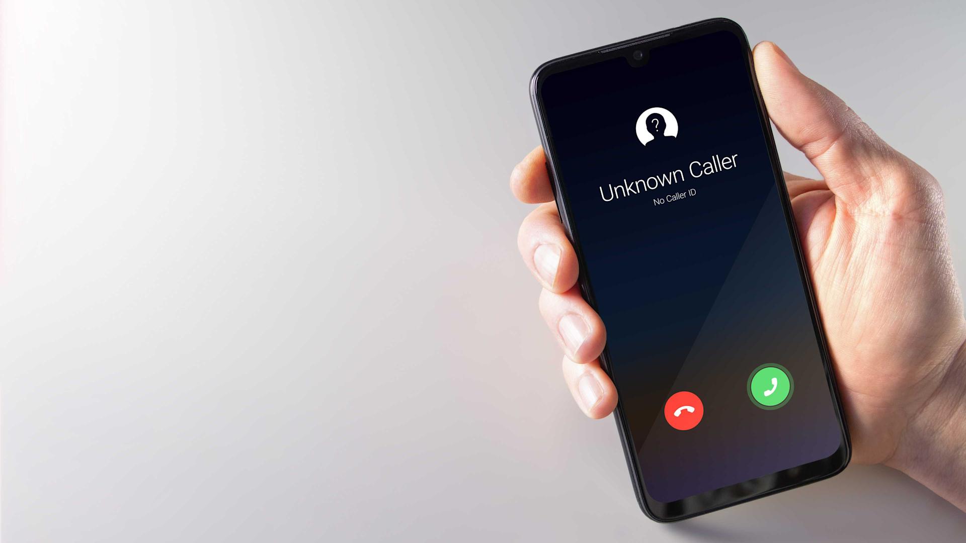 Male hand holding a smartphone with unknown caller displayed on screen