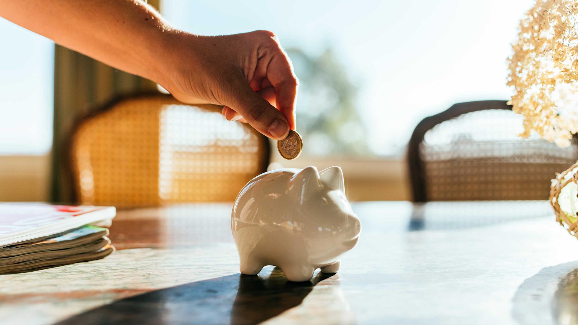 Woman putting savings in a white piggy bank.