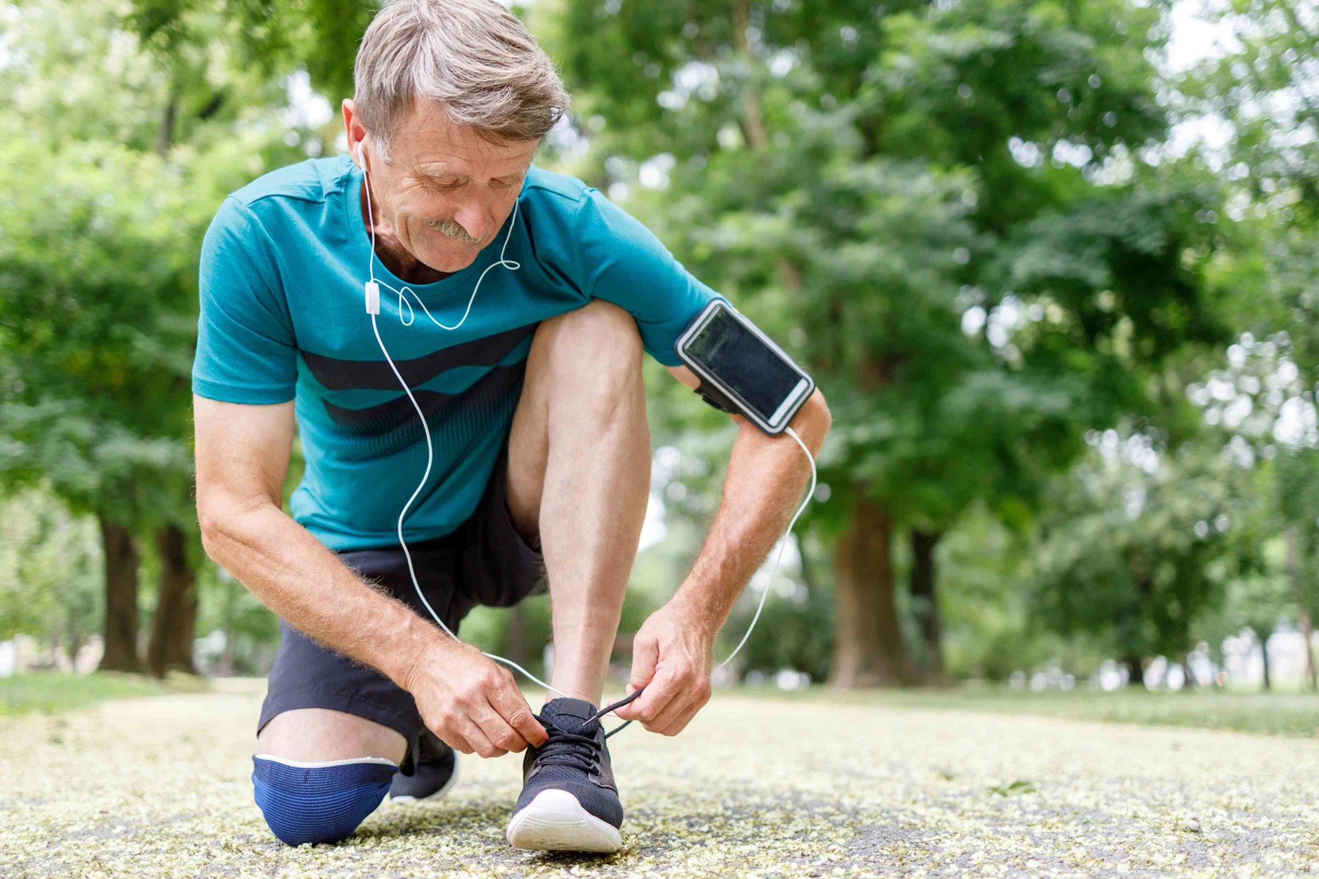 A man in jogging clothing bends down and ties his running shoes