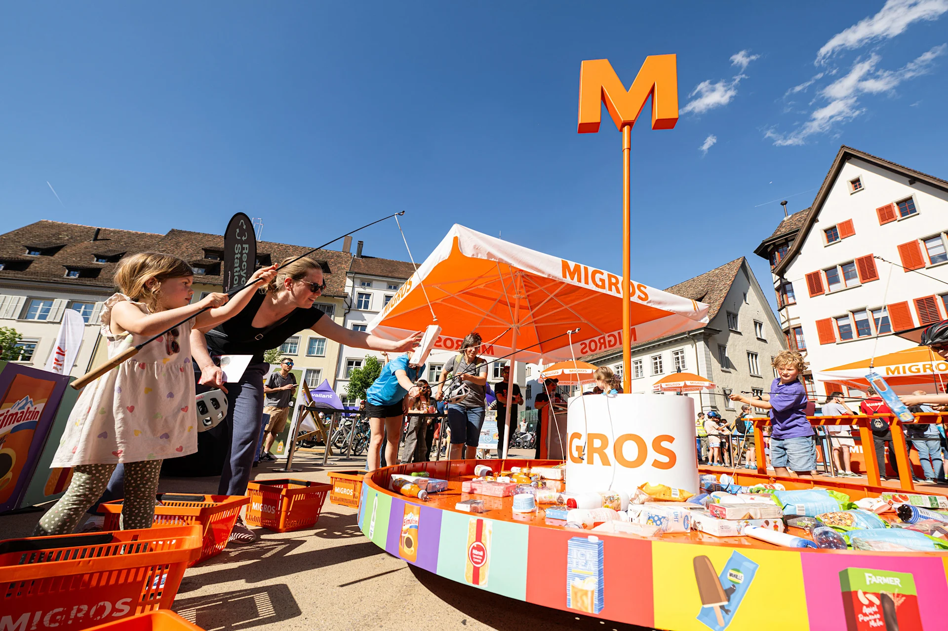 Teilnehmerinnen und Teilnehmer des slowUp fischen bei einem Spiel nach Migros Produkten