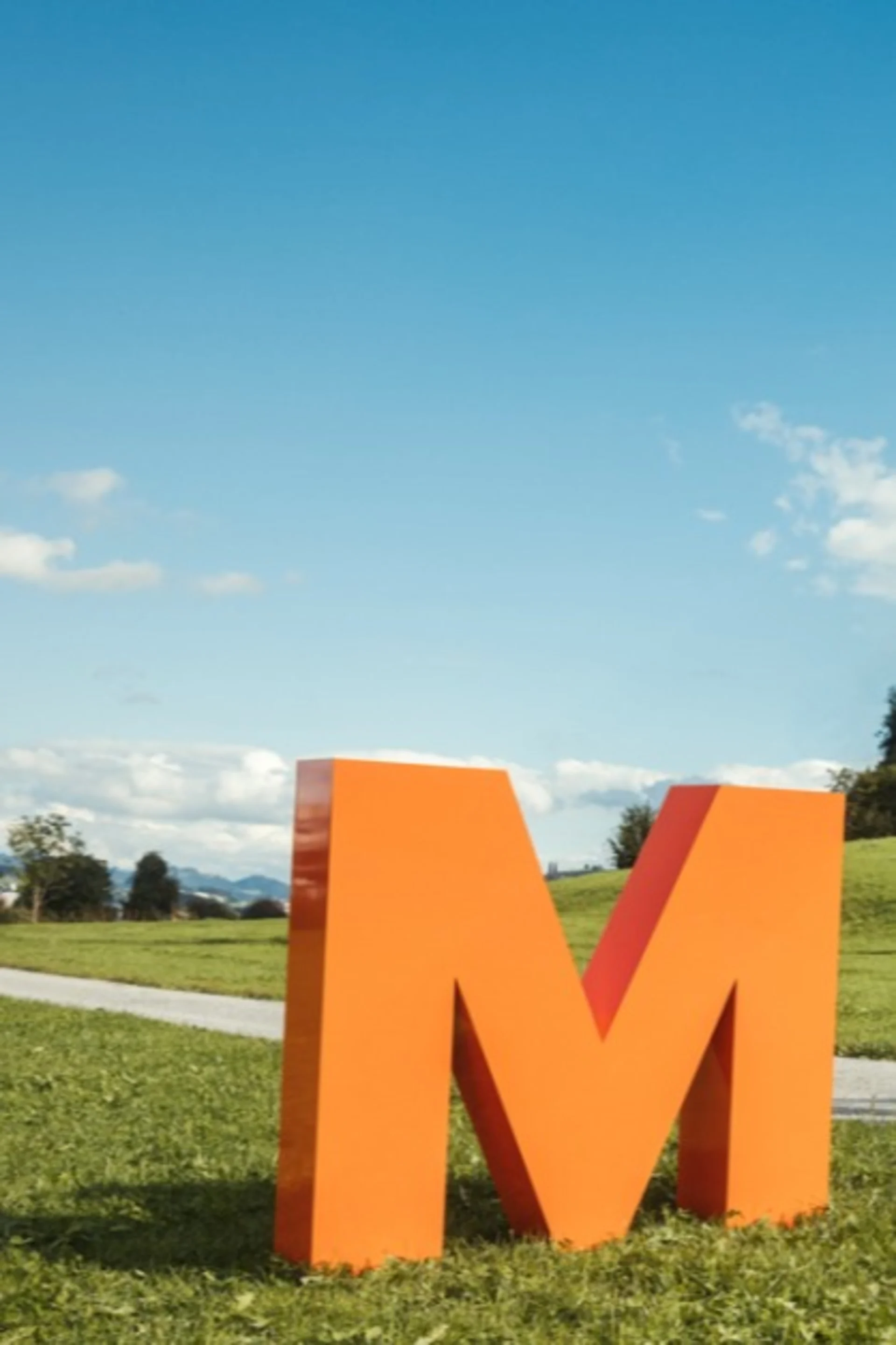 Orange Migros M on a green meadow.