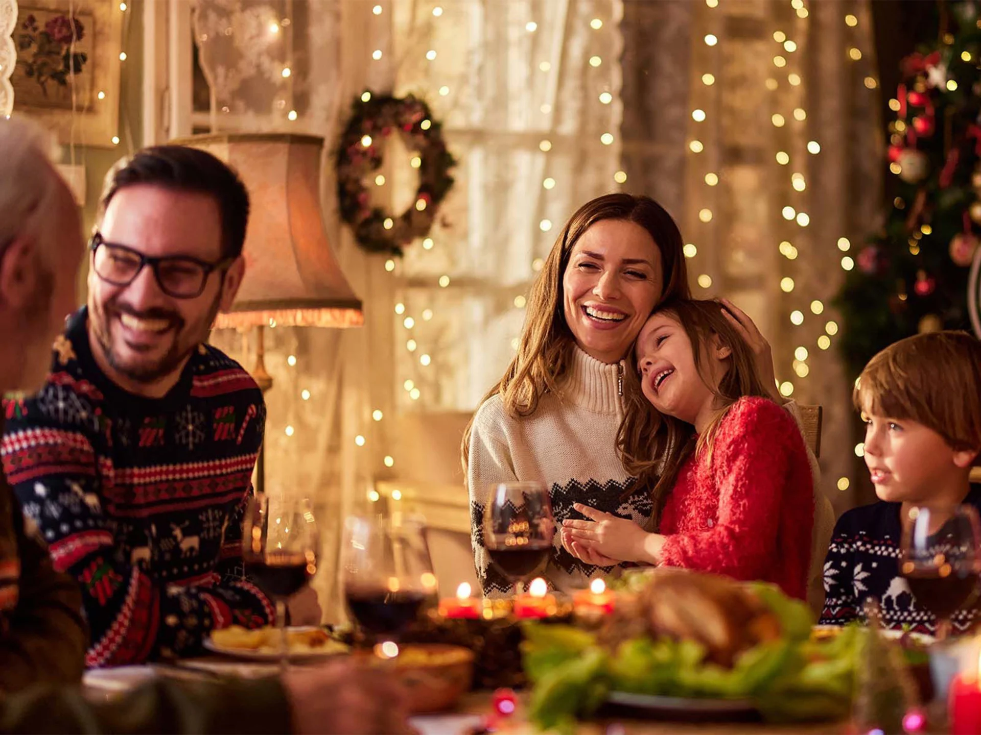 Eine Familie sitzt am festlich gedeckten Tisch mit Weihnachtsdekoration