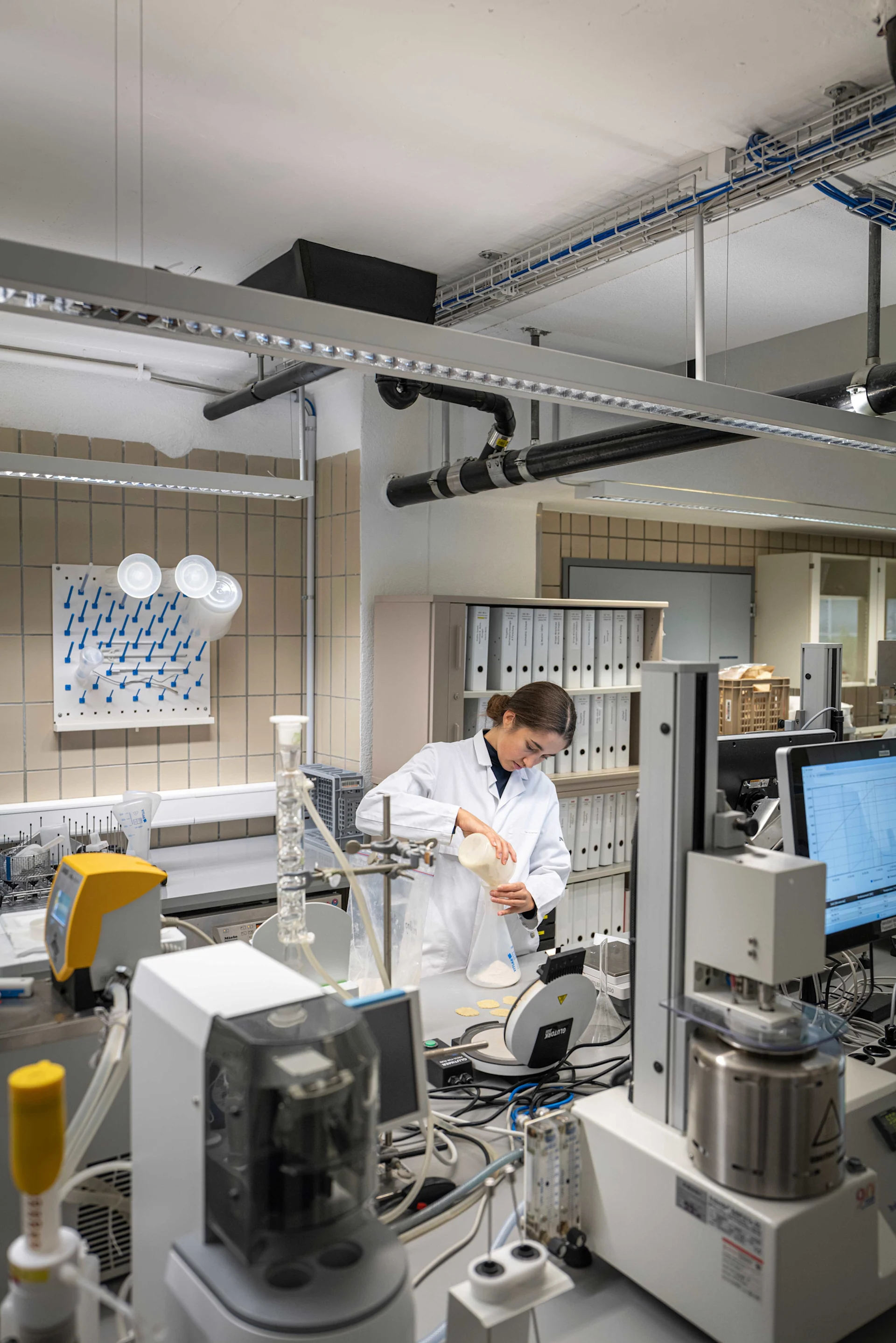 Un dipendente si trova nel laboratorio della farina e versa la farina in un barattolo