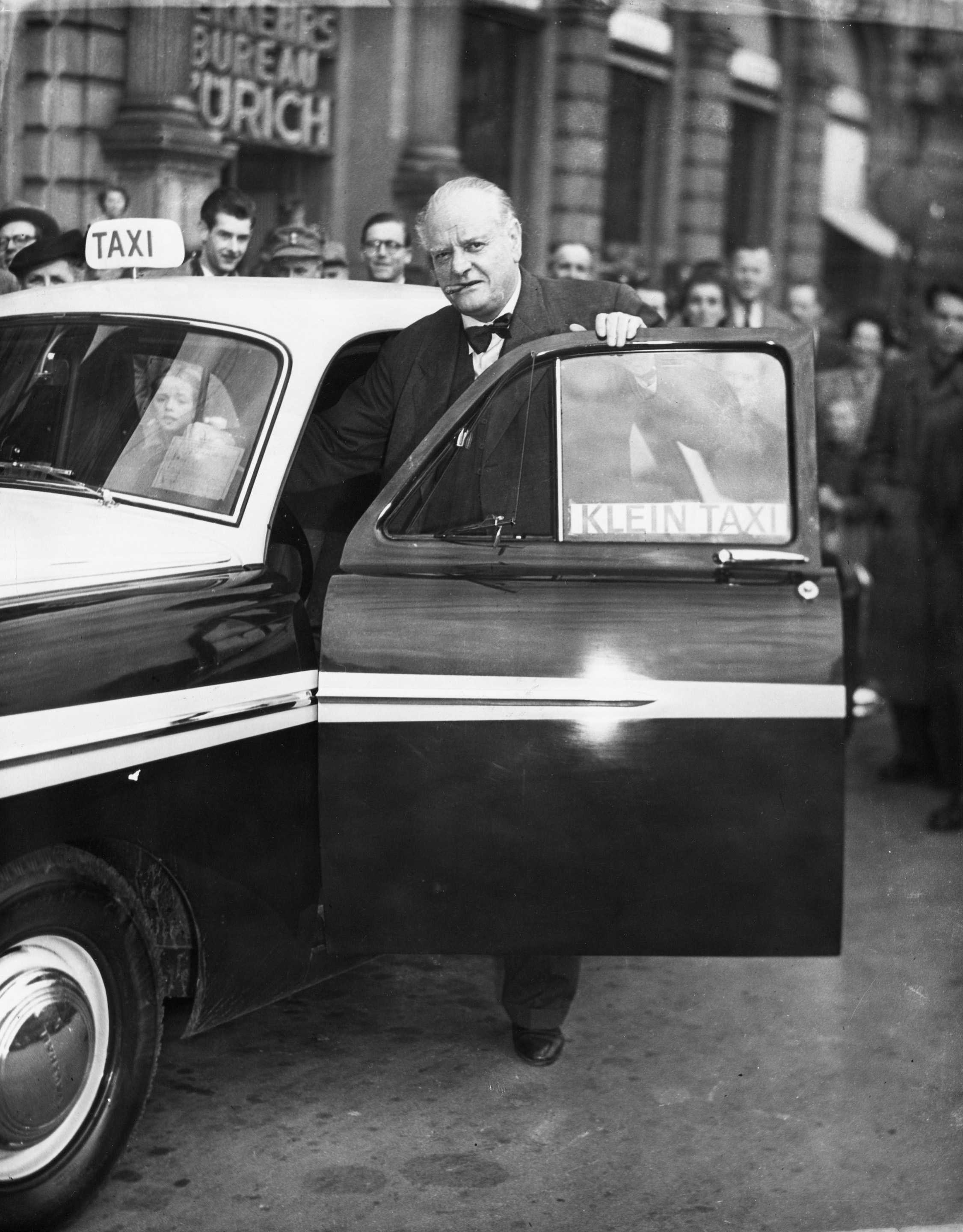 Une photographie en noir et blanc de Gottlieb Duttweiler montant dans un taxi