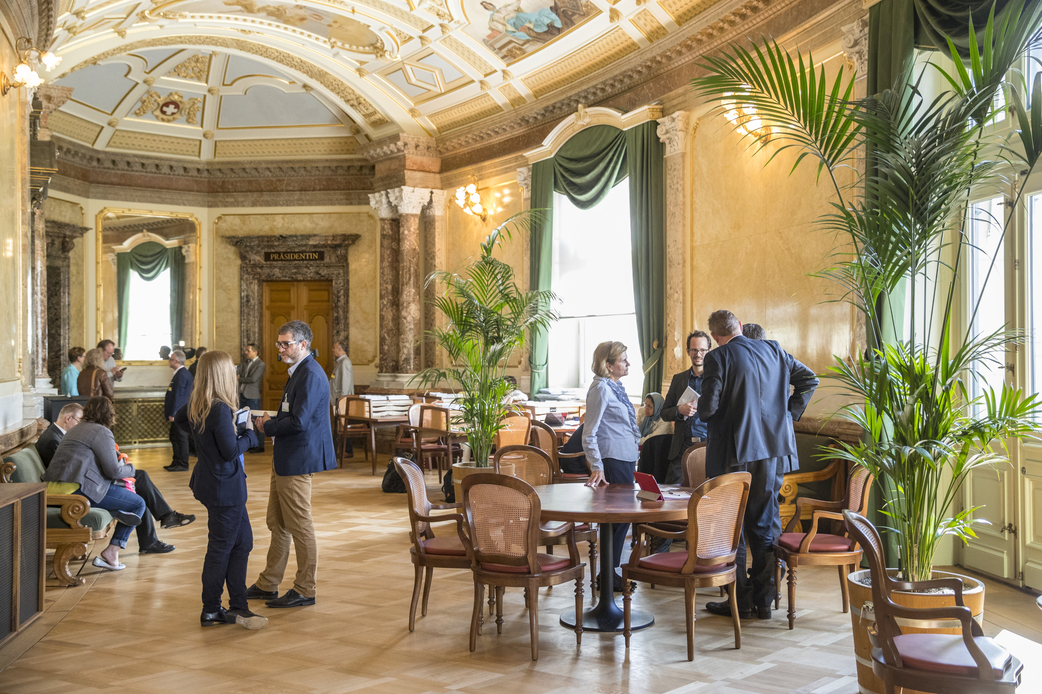 Verschiedene Politiker*innen treffen sich in einem Vorraum im Bundeshaus.