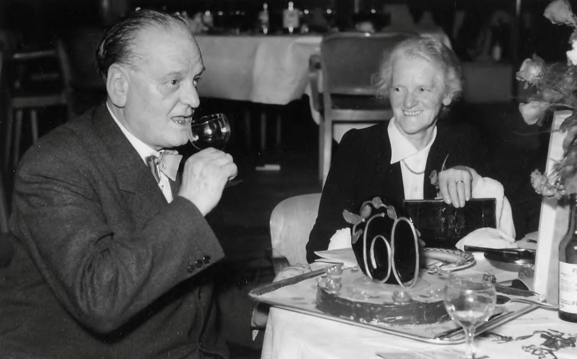 Une photographie en noir et blanc de Gottlieb Duttweiler, un verre de vin à la main.