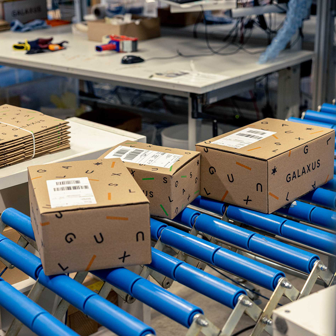 I pacchi Galaxus vengono trasportati su un nastro trasportatore blu.