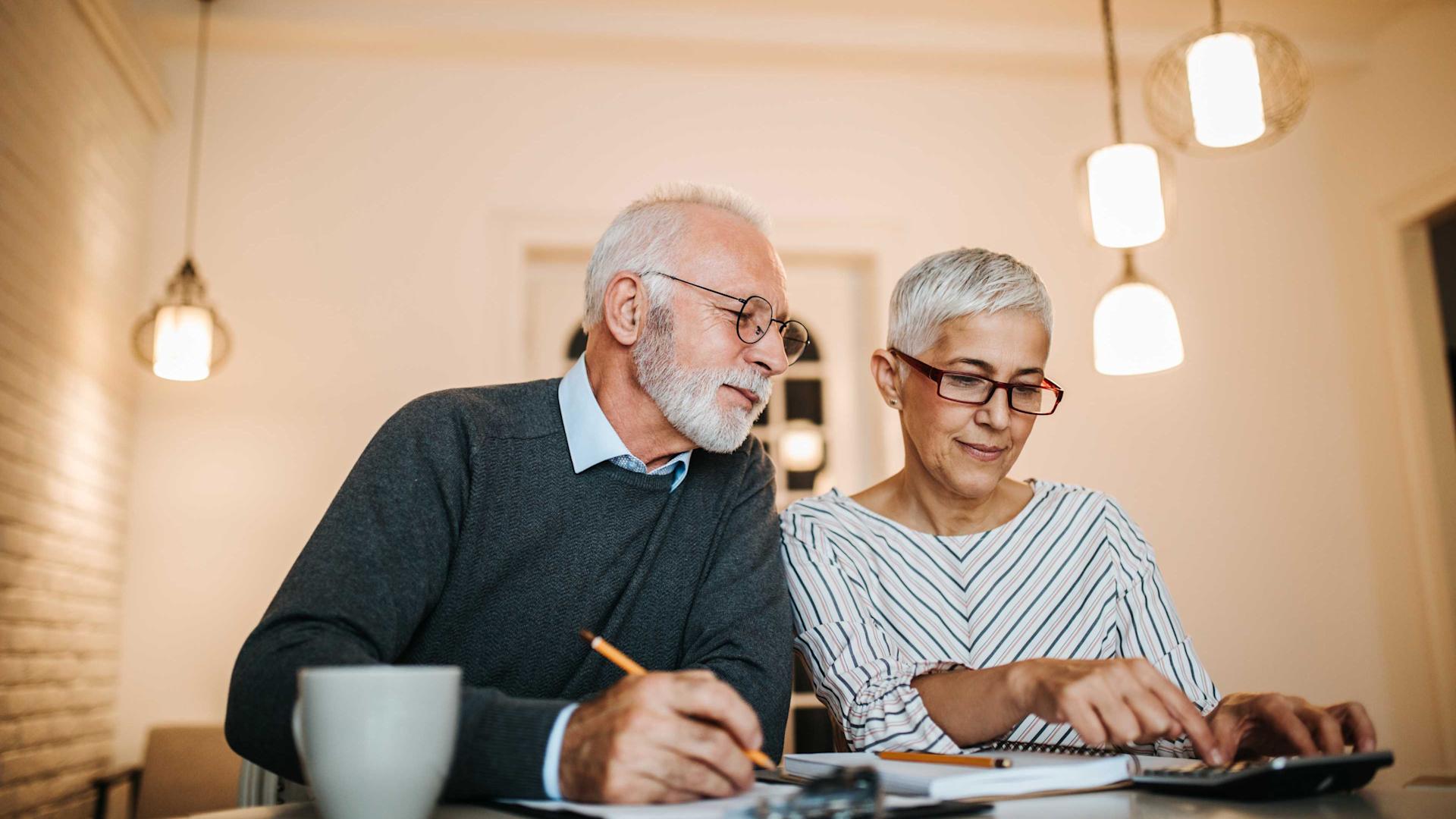Un couple âgé assis à une table fait des calculs