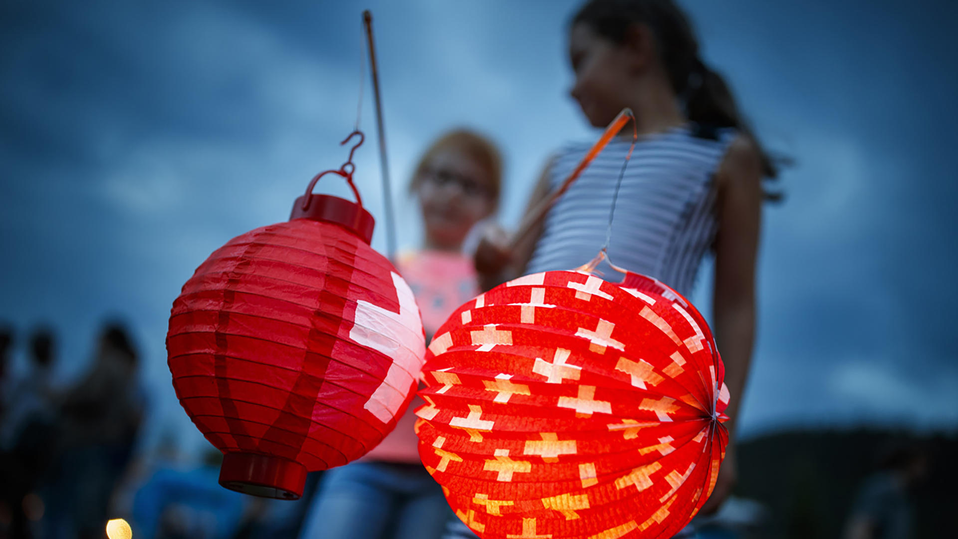 Due ragazze tengono in mano delle lanterne al tramonto durante la Festa nazionale il 1° agosto.