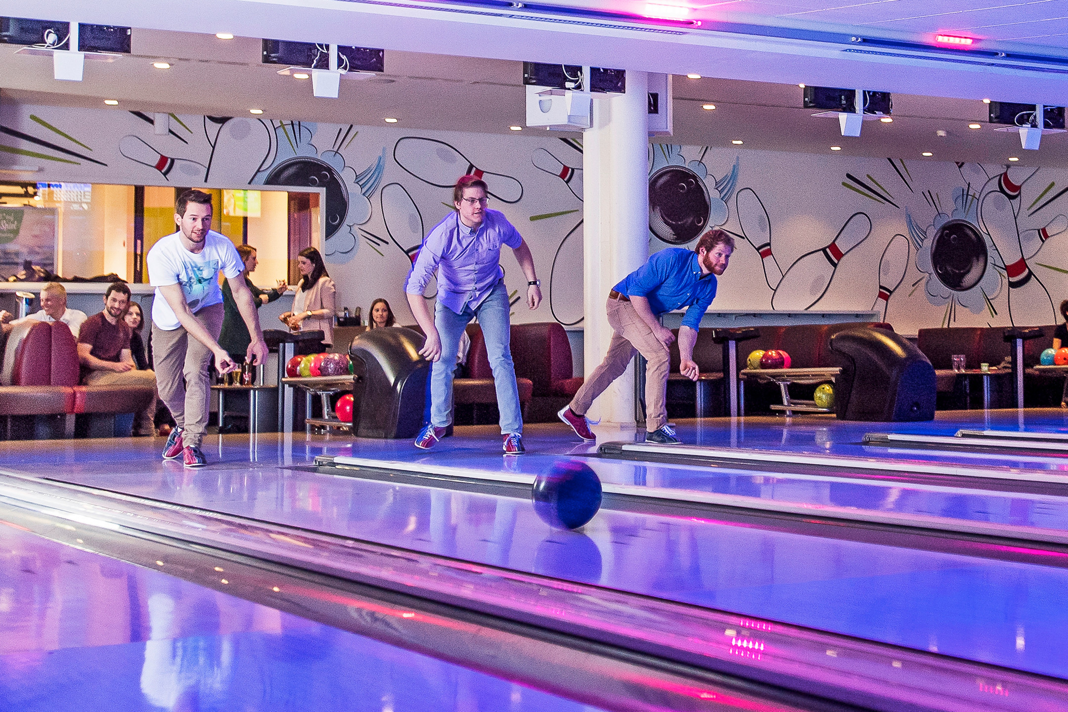 Trois hommes jouant aux quilles sur trois pistes de bowling.