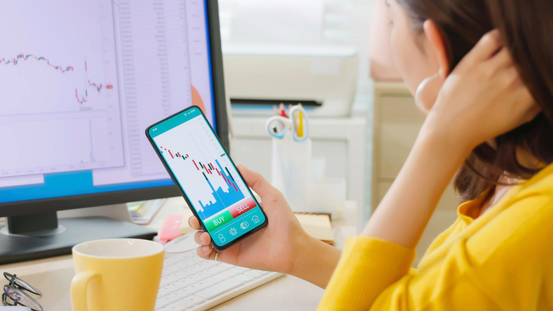 A woman looks at share prices on a mobile phone