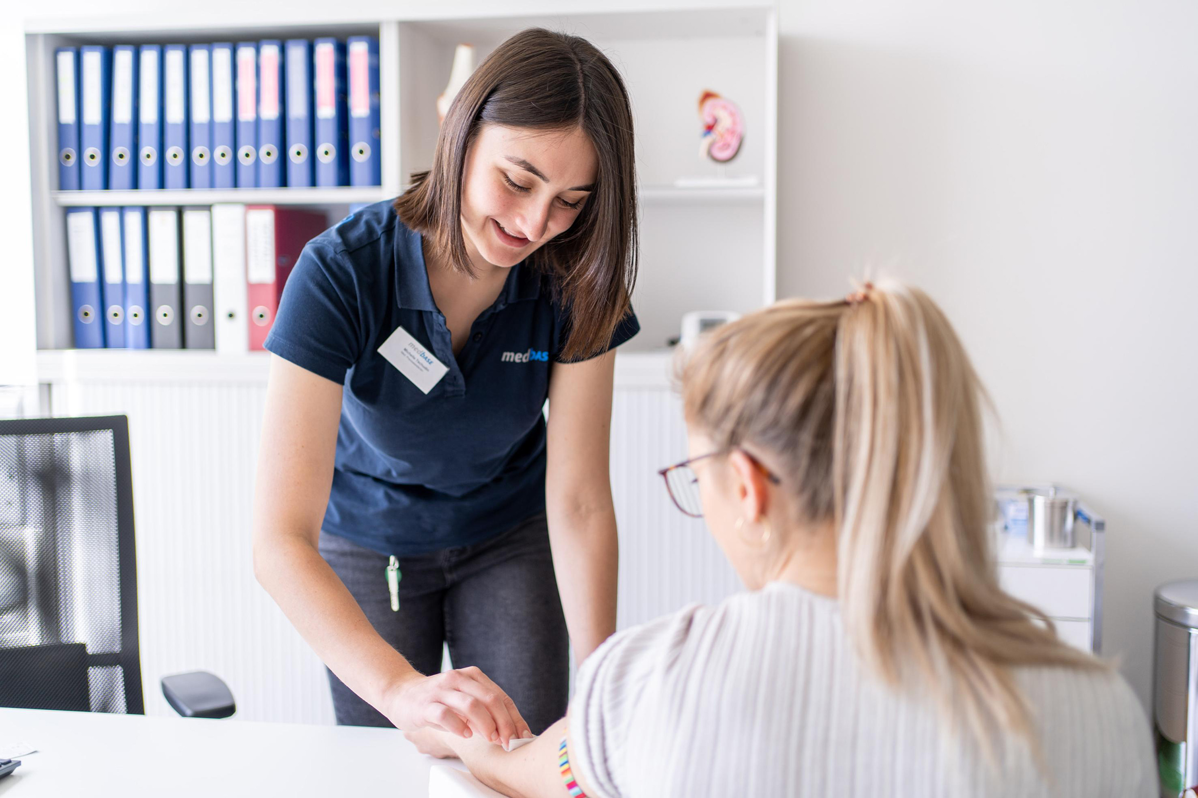 Eine medizinische Praxisassistentin bereitet eine Patientin auf die Blutentnahme vor.