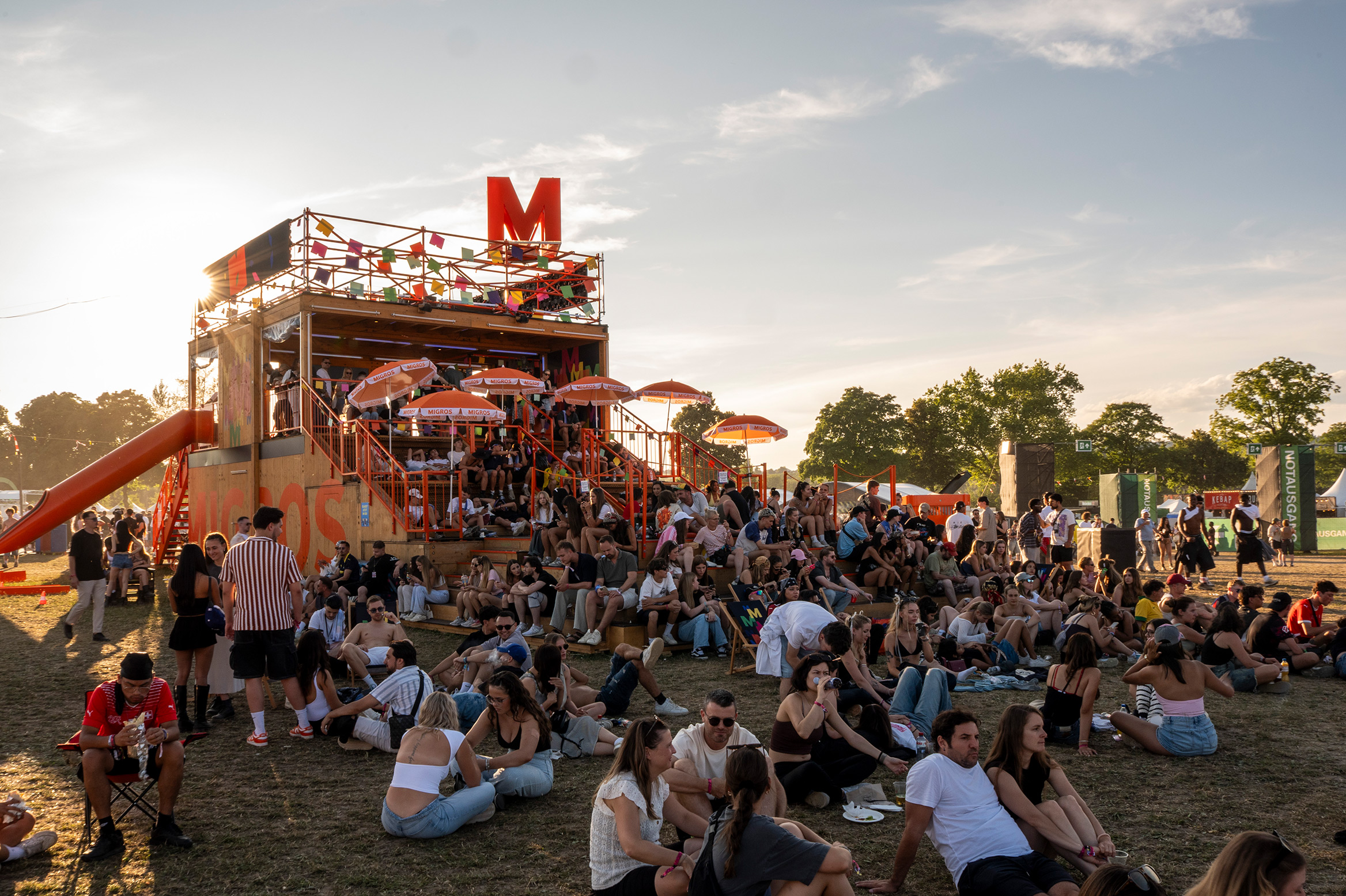 Young people are sitting in the shade at the Migros stand at Openair Frauenfeld.