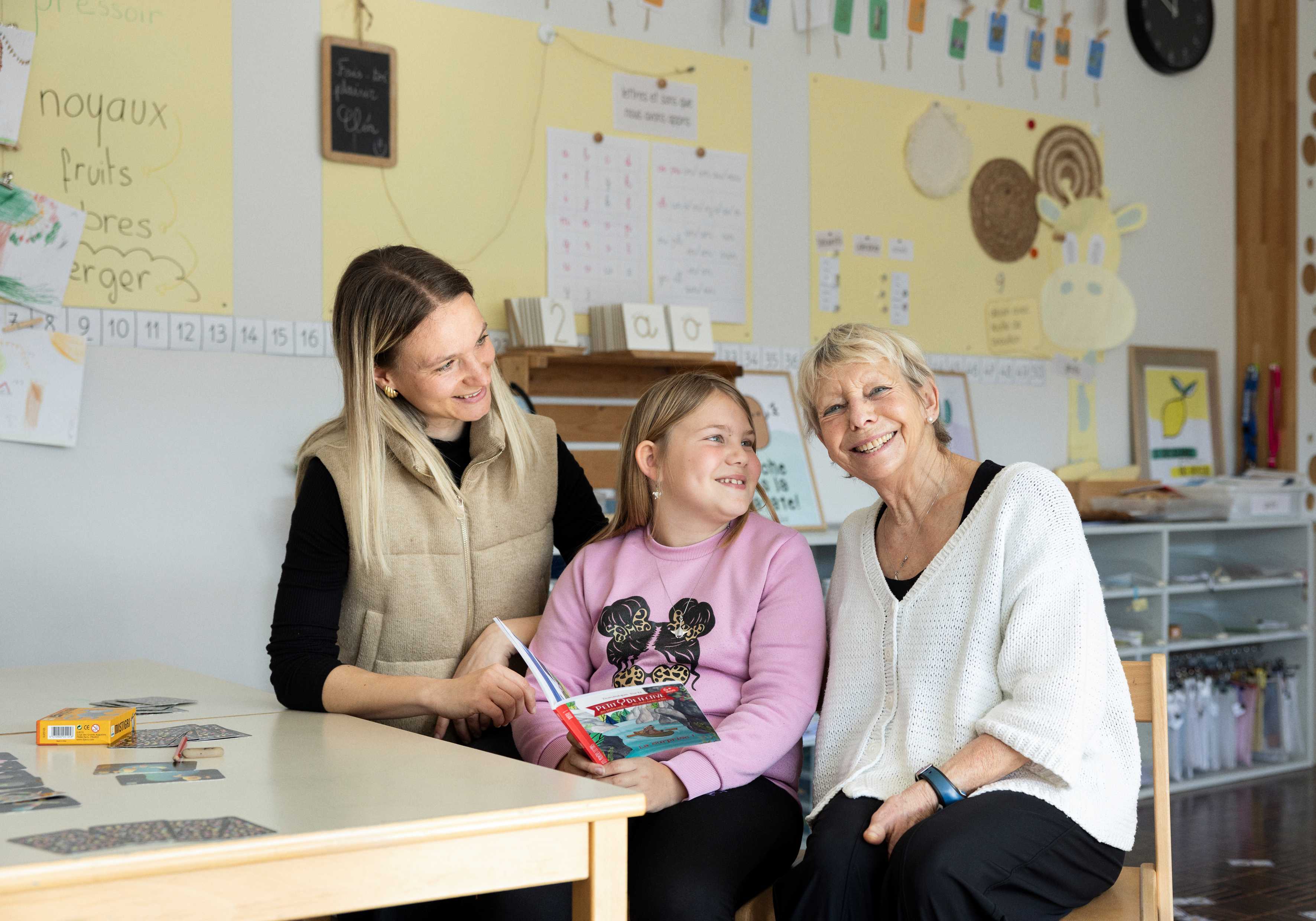 Anne-Françoise Droz im Schulzimmer zusammen mit Lehrerin Marie Negri und Schülerin Finja Riedwyl.