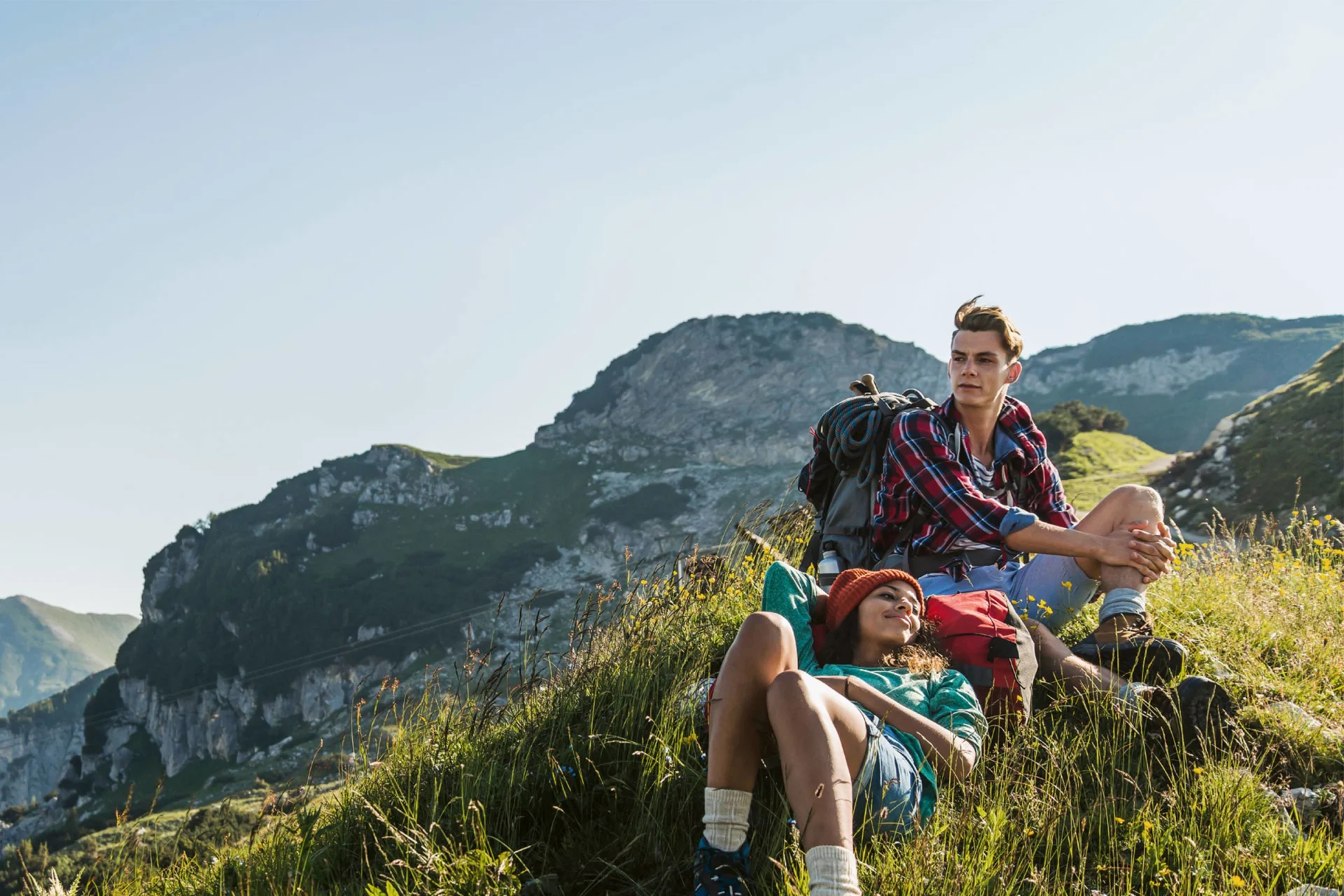 Young couple relaxing on mountain slope after a hike.