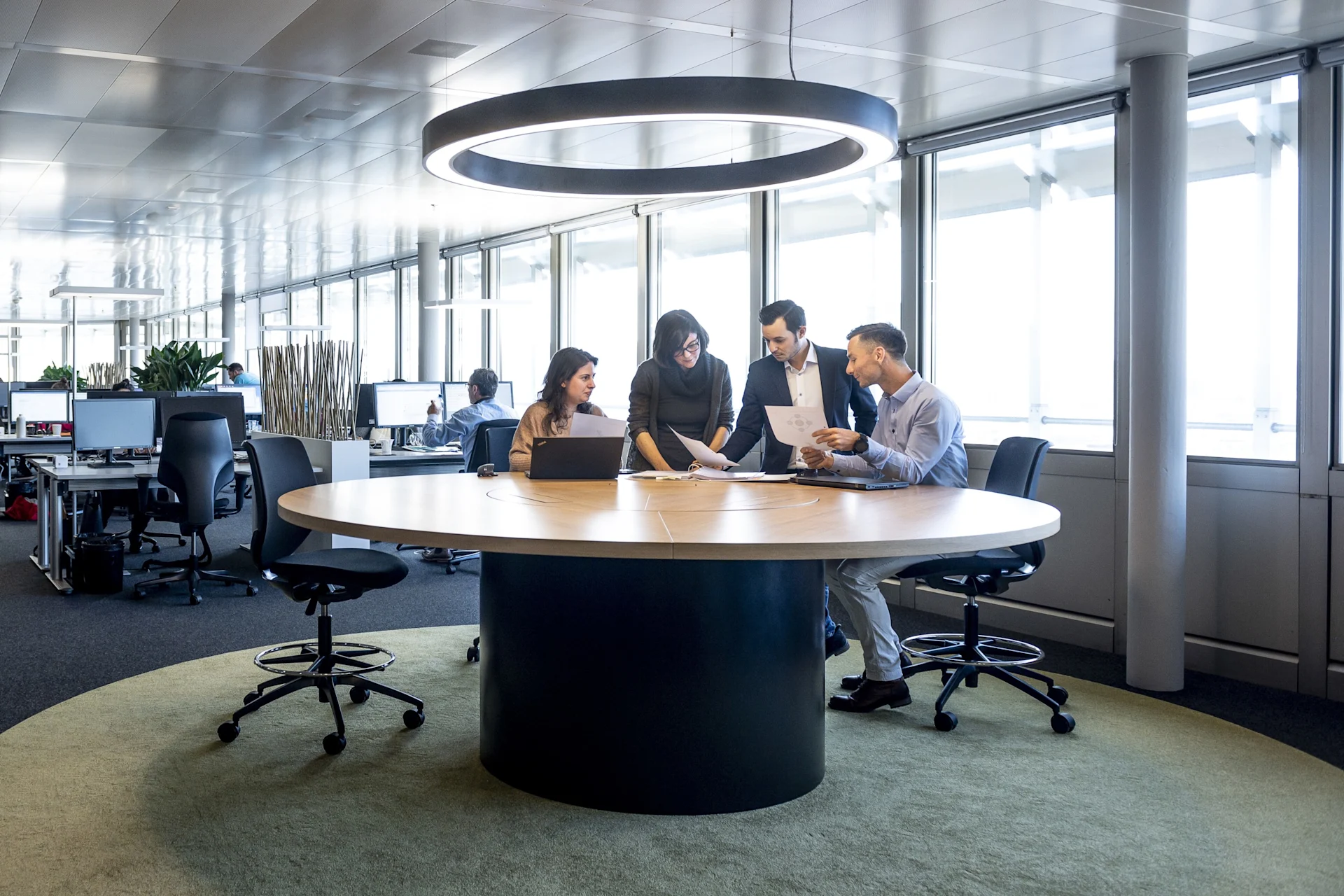 4 employees discuss a topic together at a round table