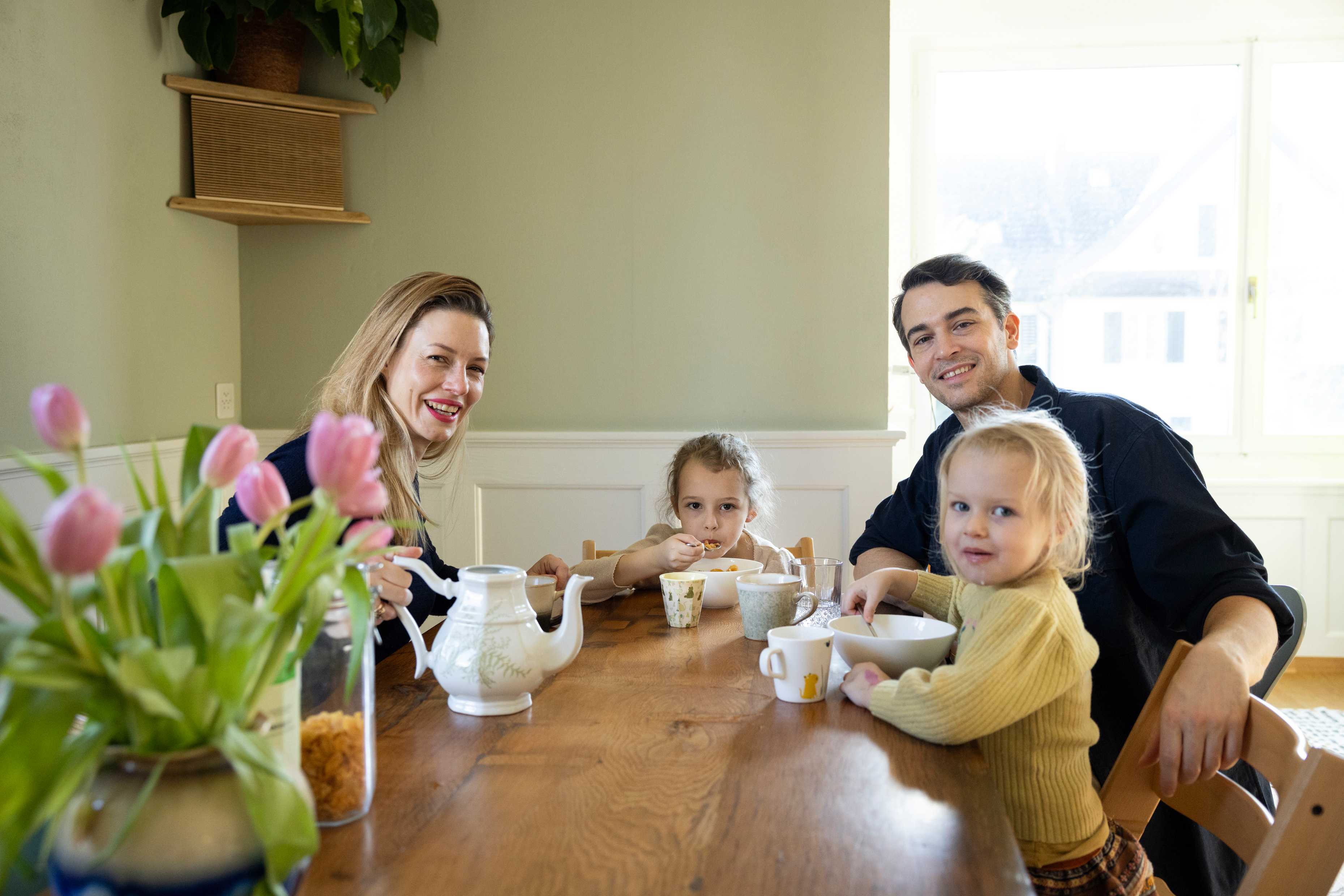 Gratia Hoschek siede al tavolo da pranzo con il marito e le due figlie.