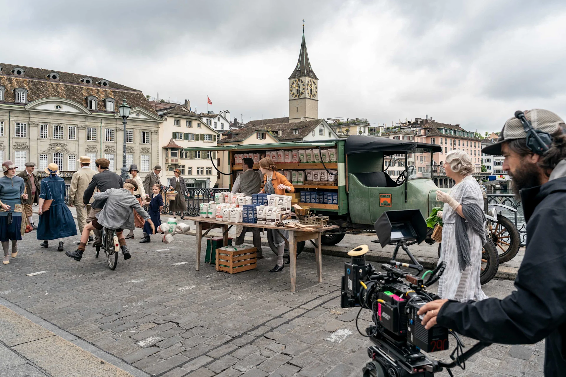Zwei Lausbuben sausen auf einem klapprigen Velo vorbei und fegen Auslagen vom Verkaufstisch