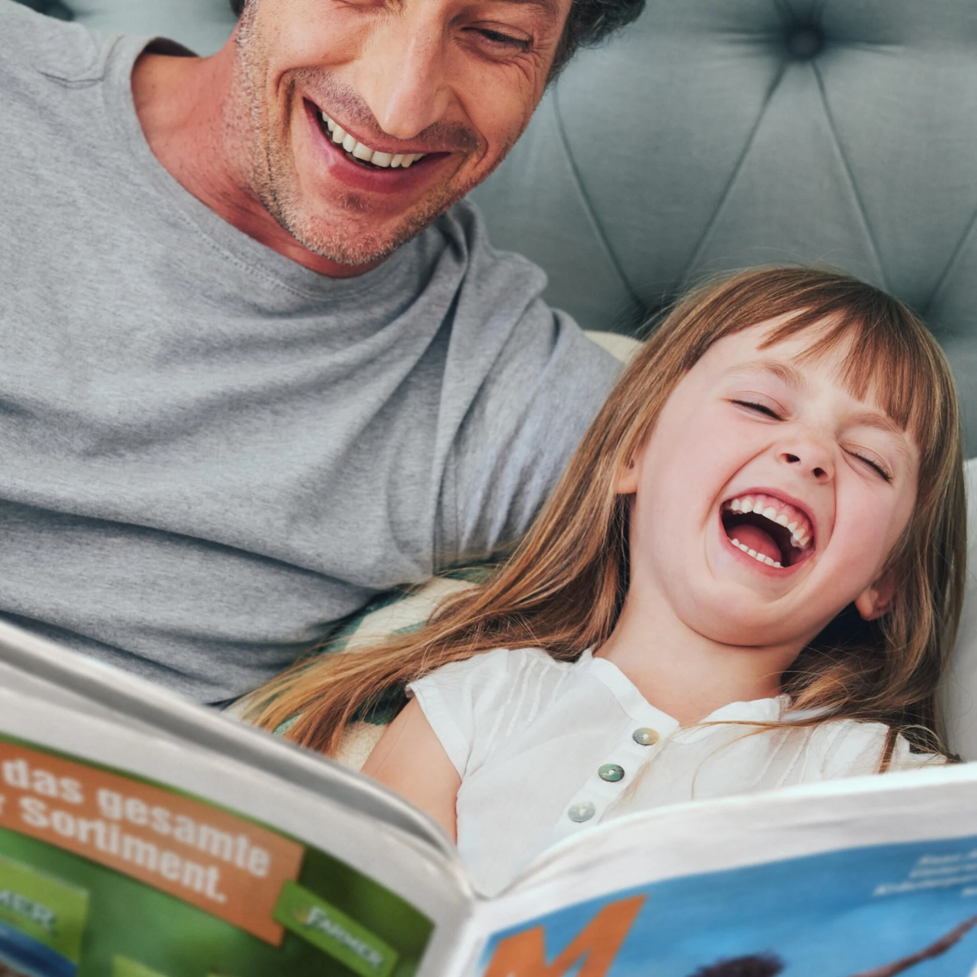 Un homme et un enfant rient d'un article de magazine