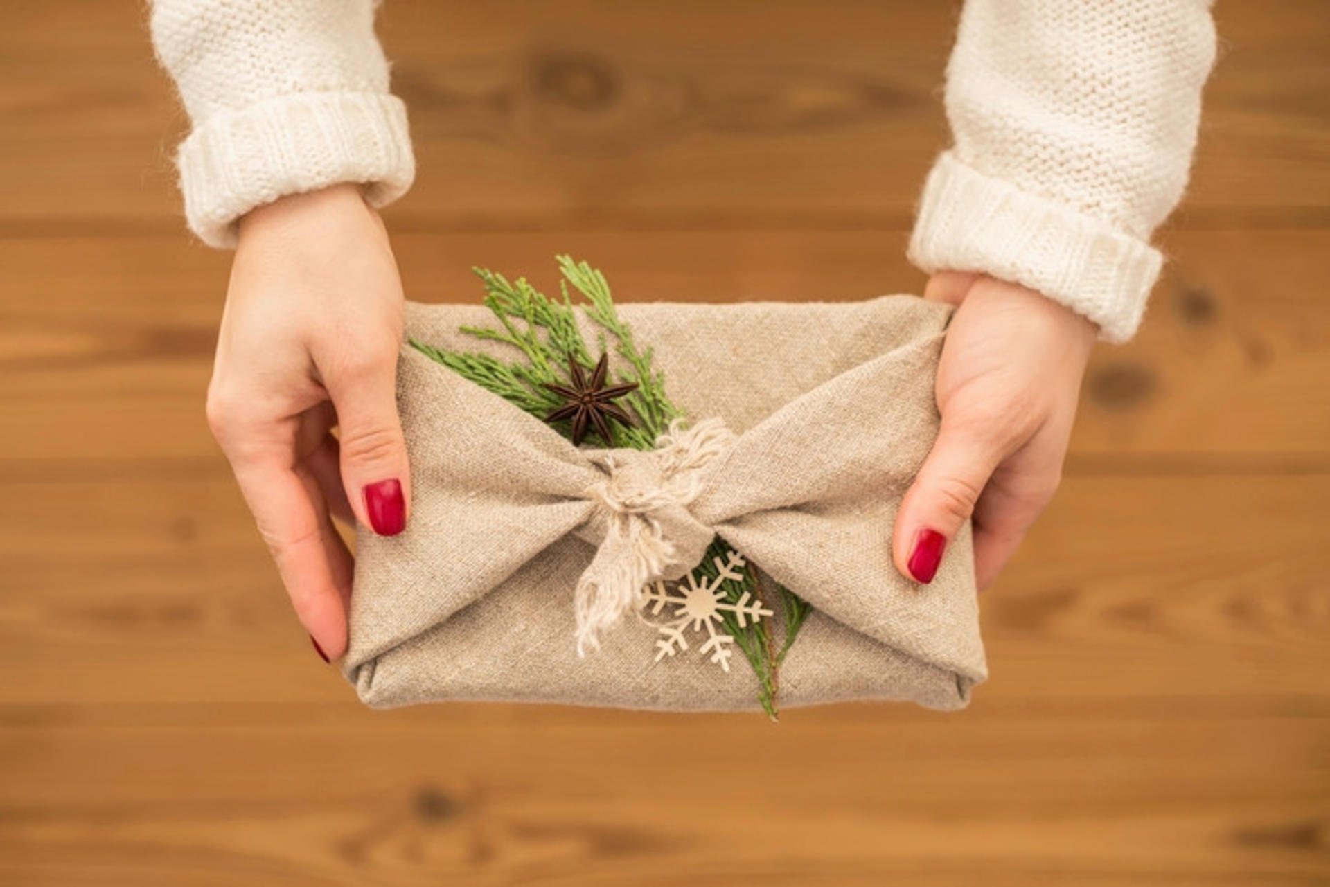 Eine Frau hält ein in einen Jutesack verpacktes Geschenk in den Händen.