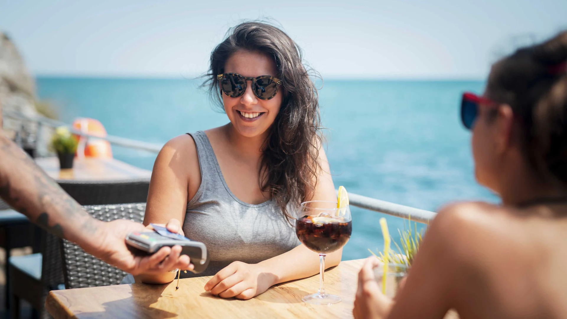 Una donna paga un drink con la sua carta mentre è in vacanza