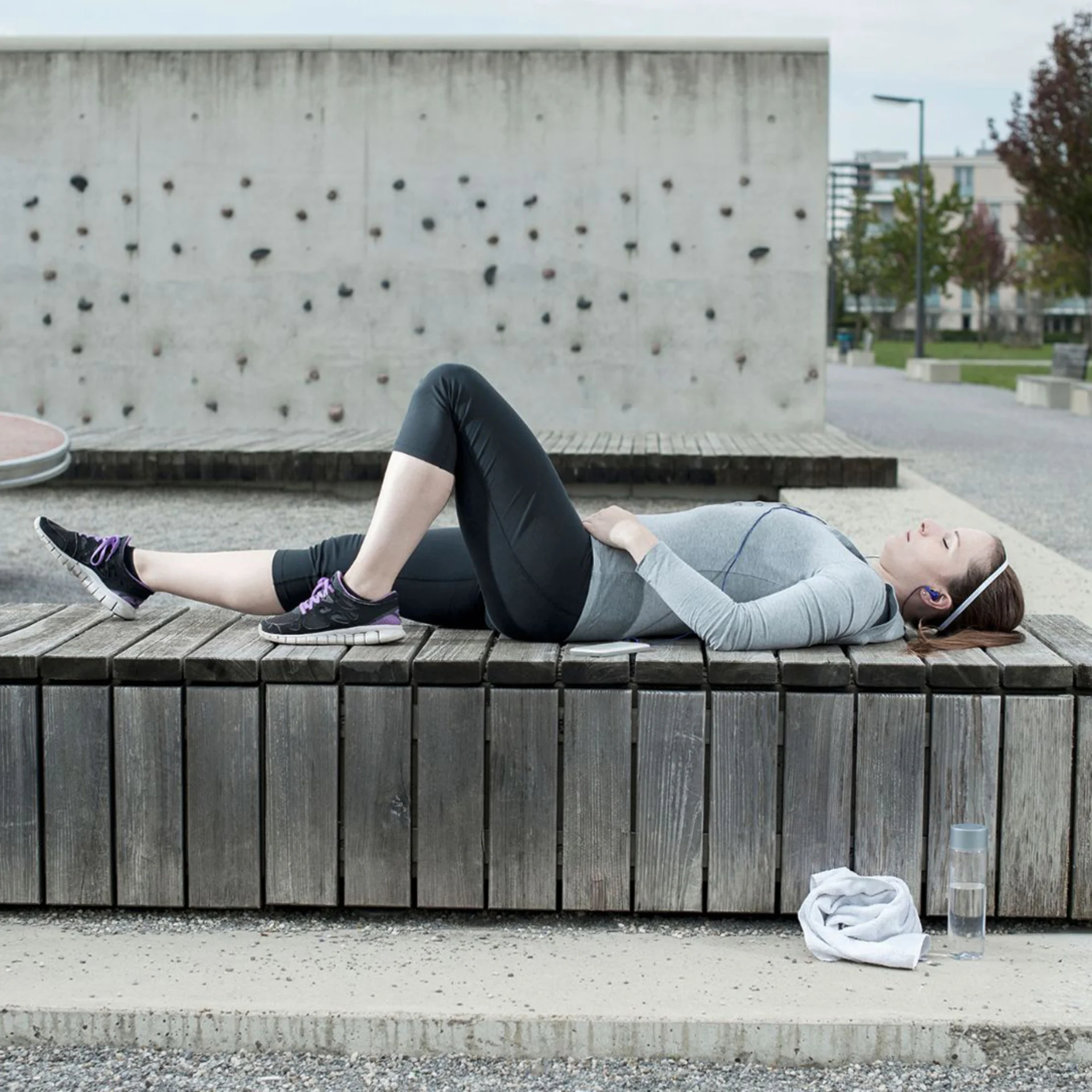 A woman lies on a bench after exercising