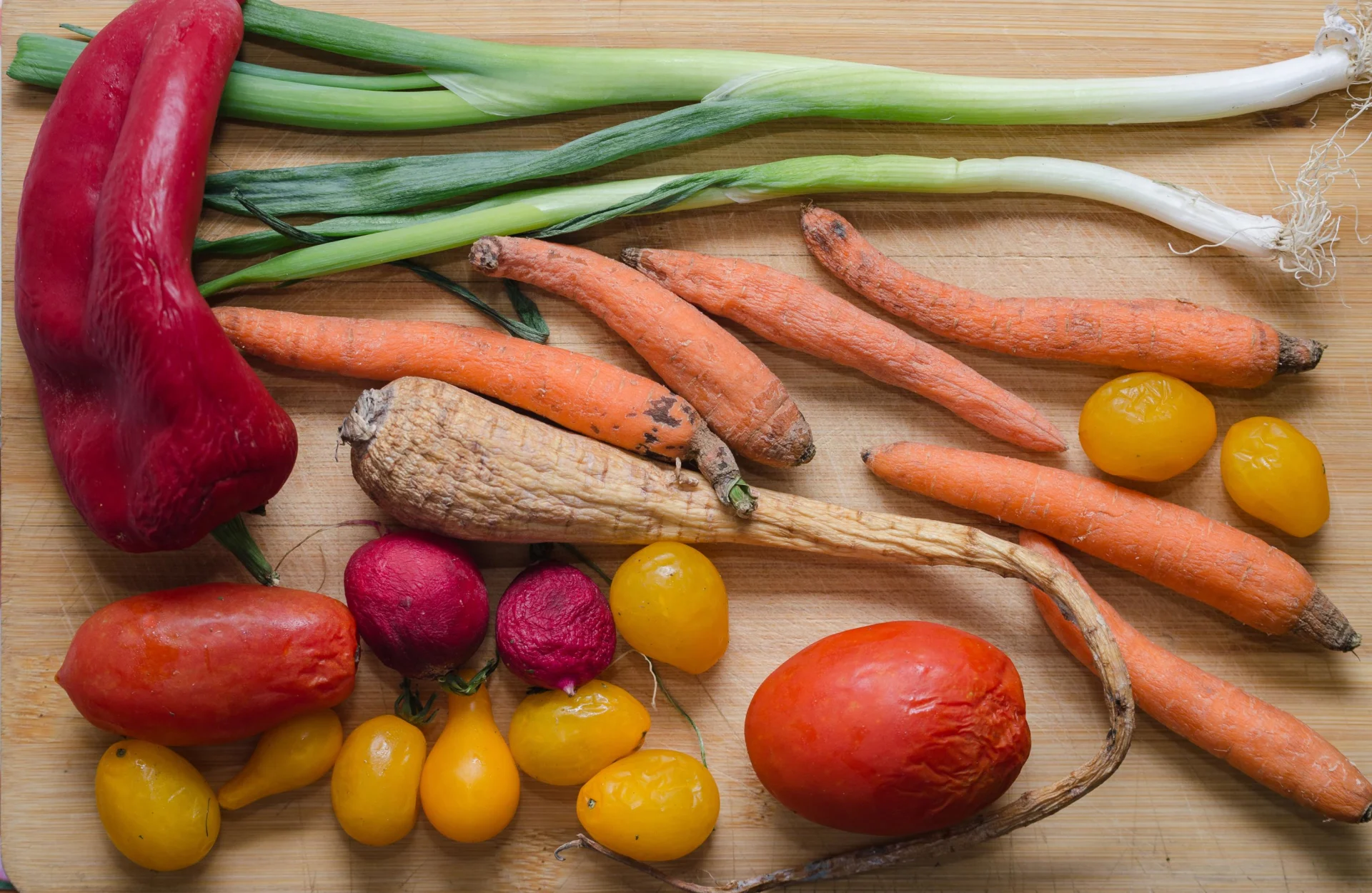 Verdure avvizzite come carote, porri, peperoni e pomodori giacciono su un tavolo