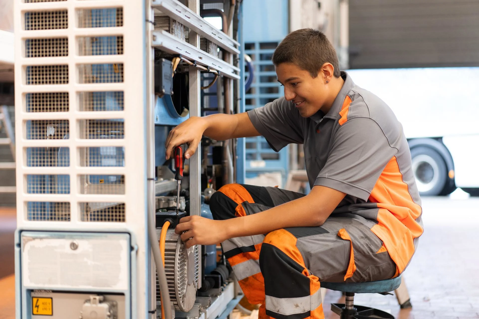 An apprentice repairs a machine.