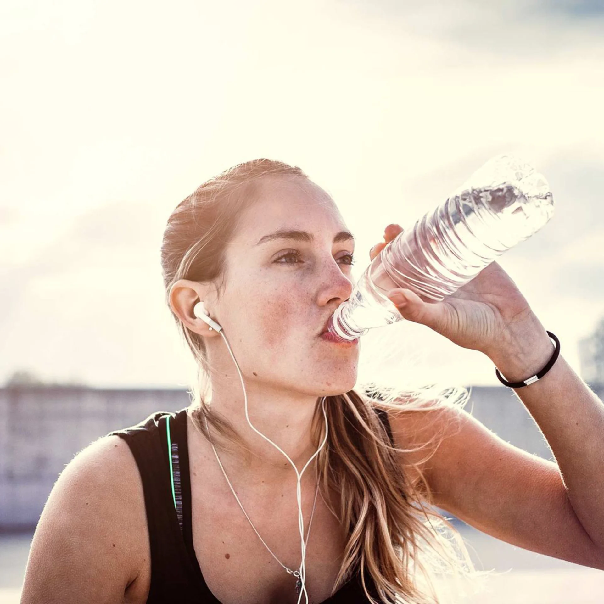 A young woman drinks water from a bottle after exercising