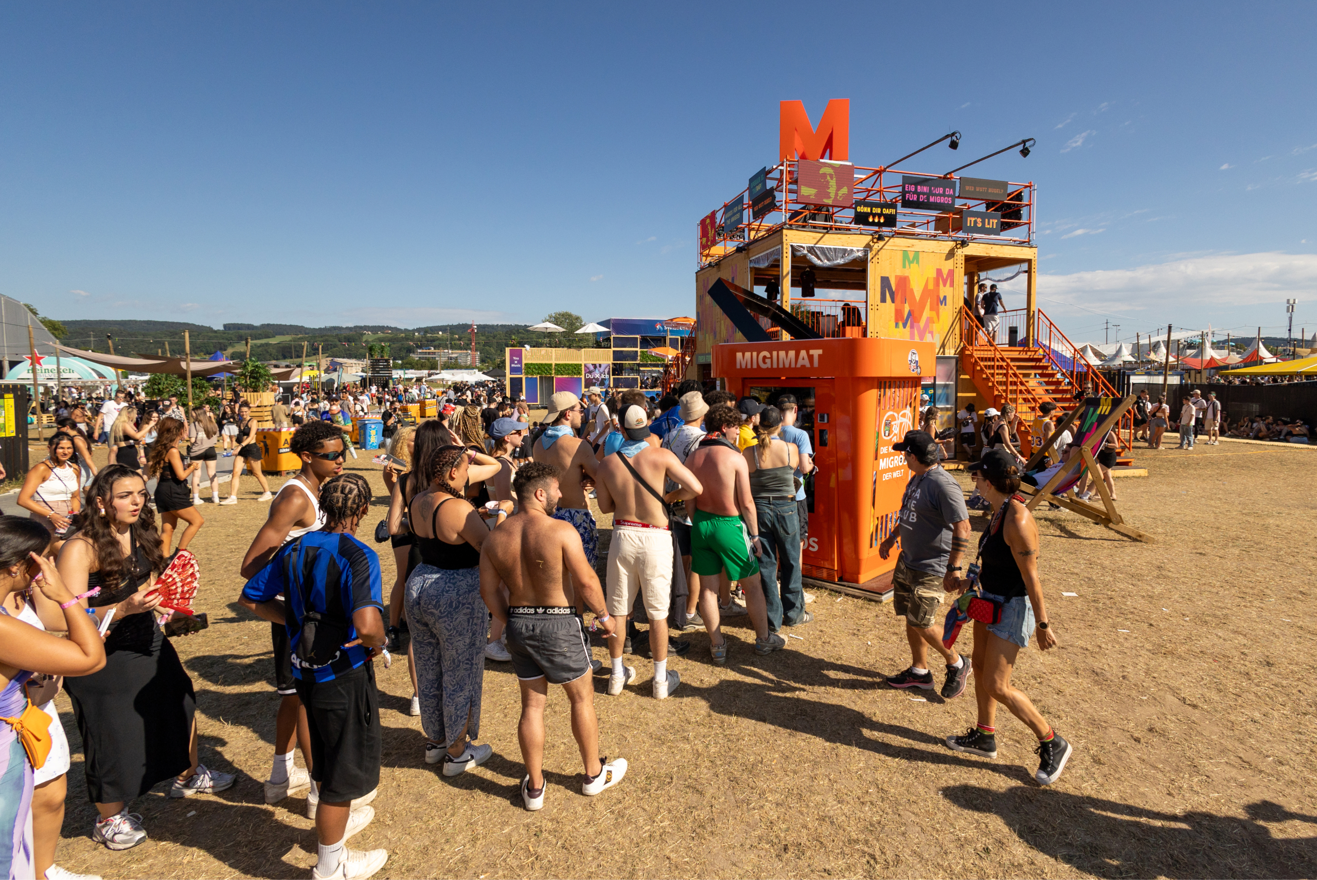 Lors d’un festival, des jeunes font la queue devant un distributeur automatique Migros. 