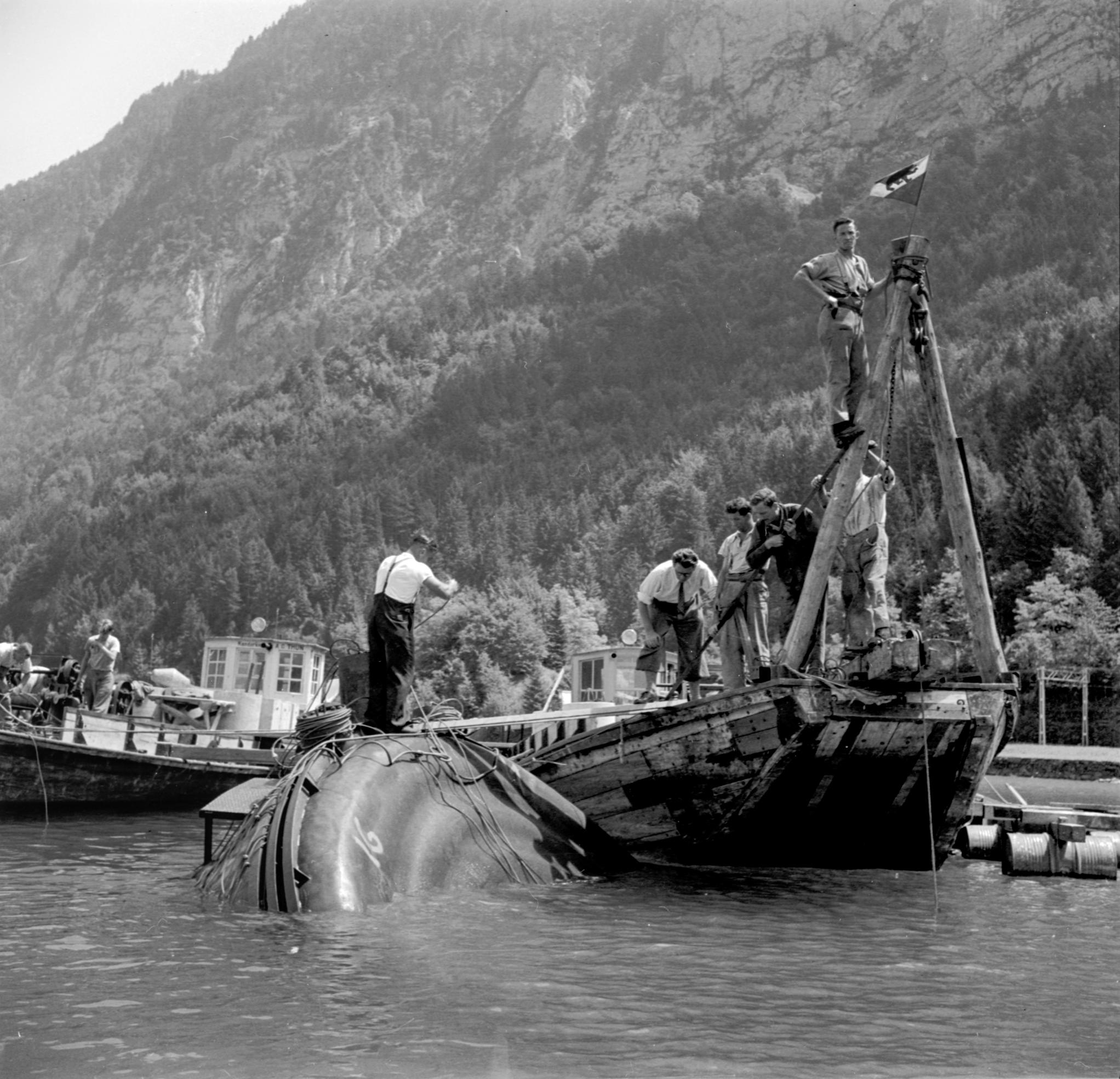 A black-and-white photograph of tanks filled with emergency supplies being sunk into the lake.