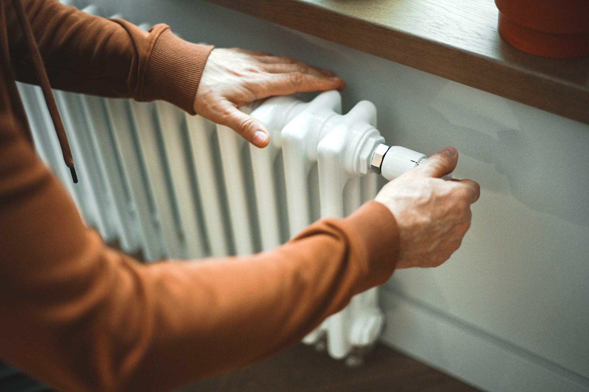 Una persona imposta la temperatura di un termosifone.
