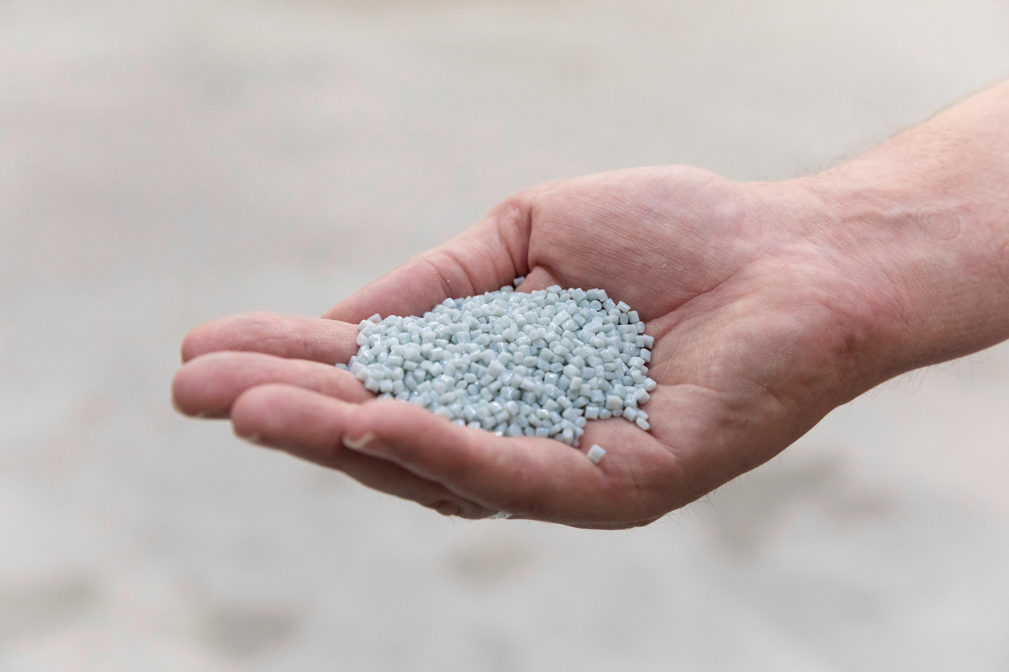 Une main tient de minuscules perles bleues