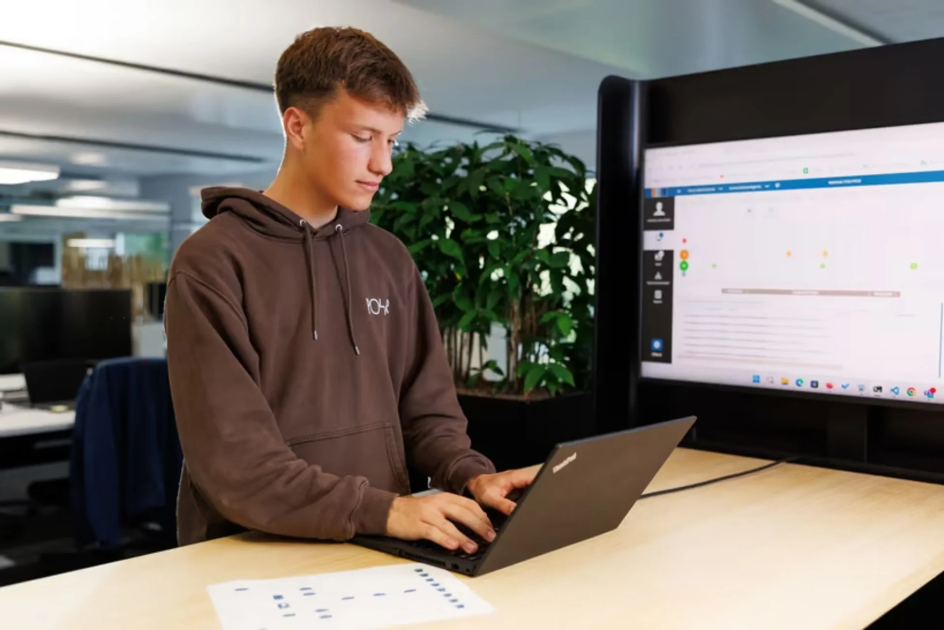 Un collaborateur travaille sur un ordinateur portable à un pupitre debout