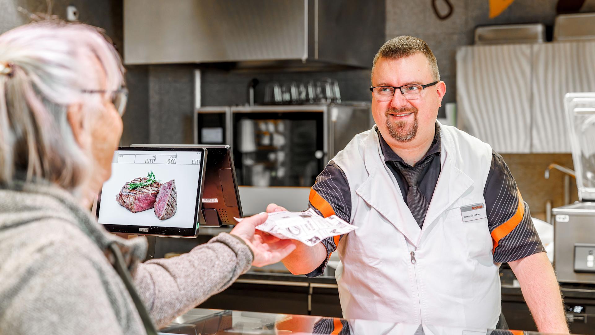 Le vendeur de viande Alexander Löhder au comptoir de la viande avec une cliente.