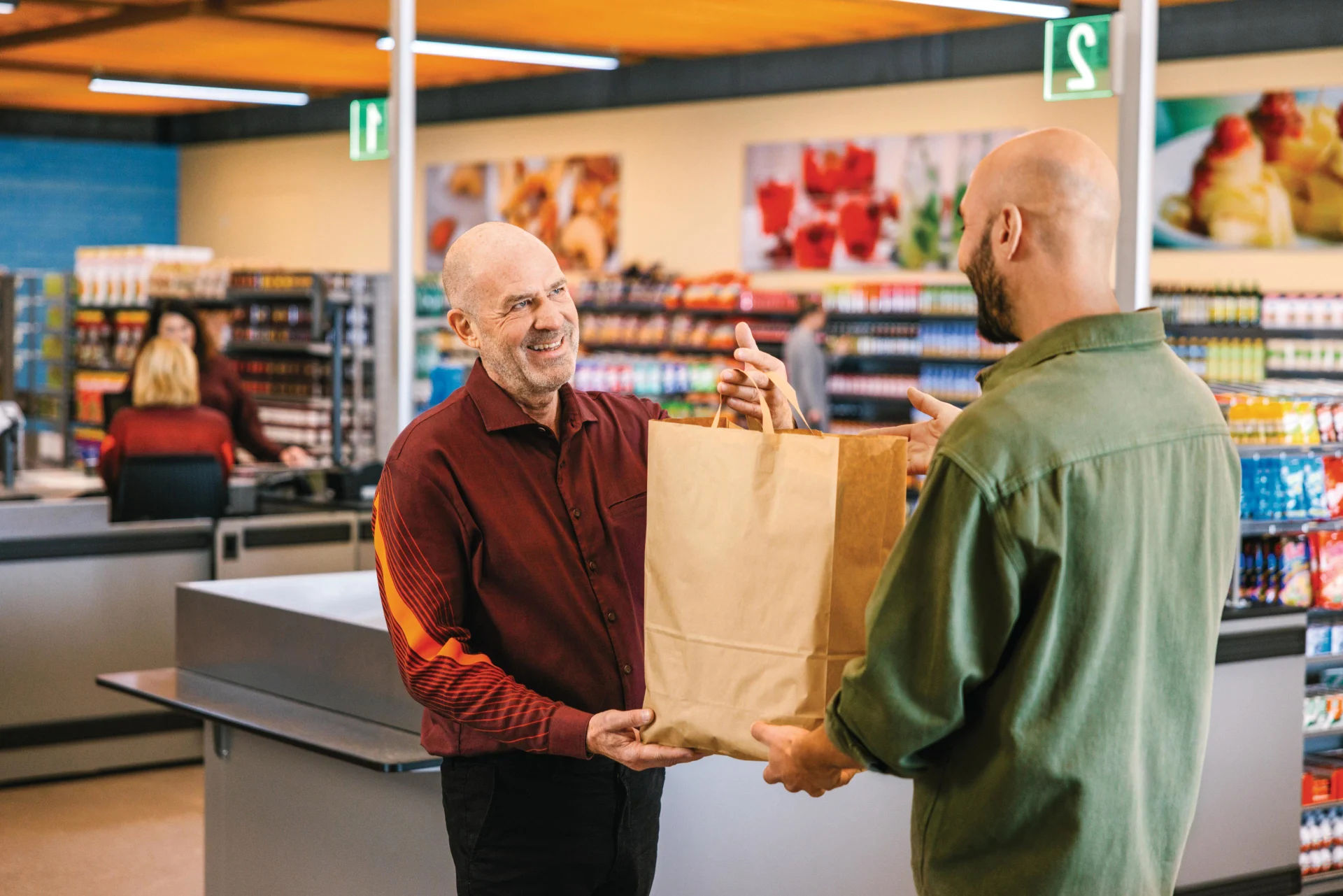 Un collaborateur Migros remet au client le sac de courses plein