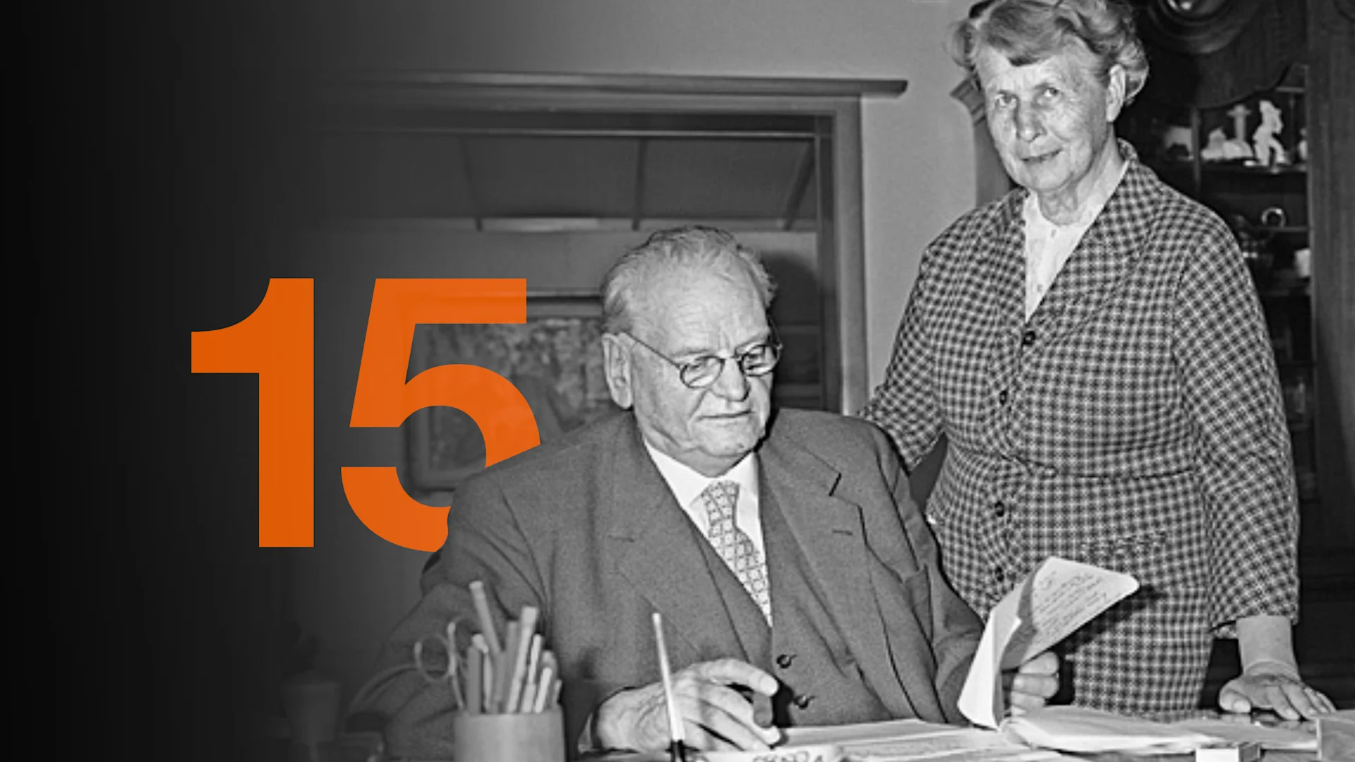 © Archive FMC A black-and-white photograph of Gottlieb and Adele Duttweiler in an office. The number 15 is superimposed in orange into the background.