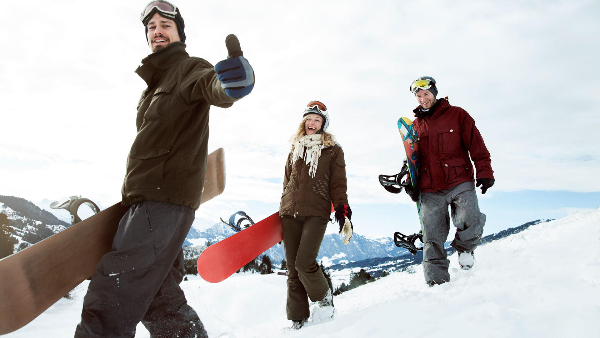 Tre adolescenti con gli snowboard nella neve.