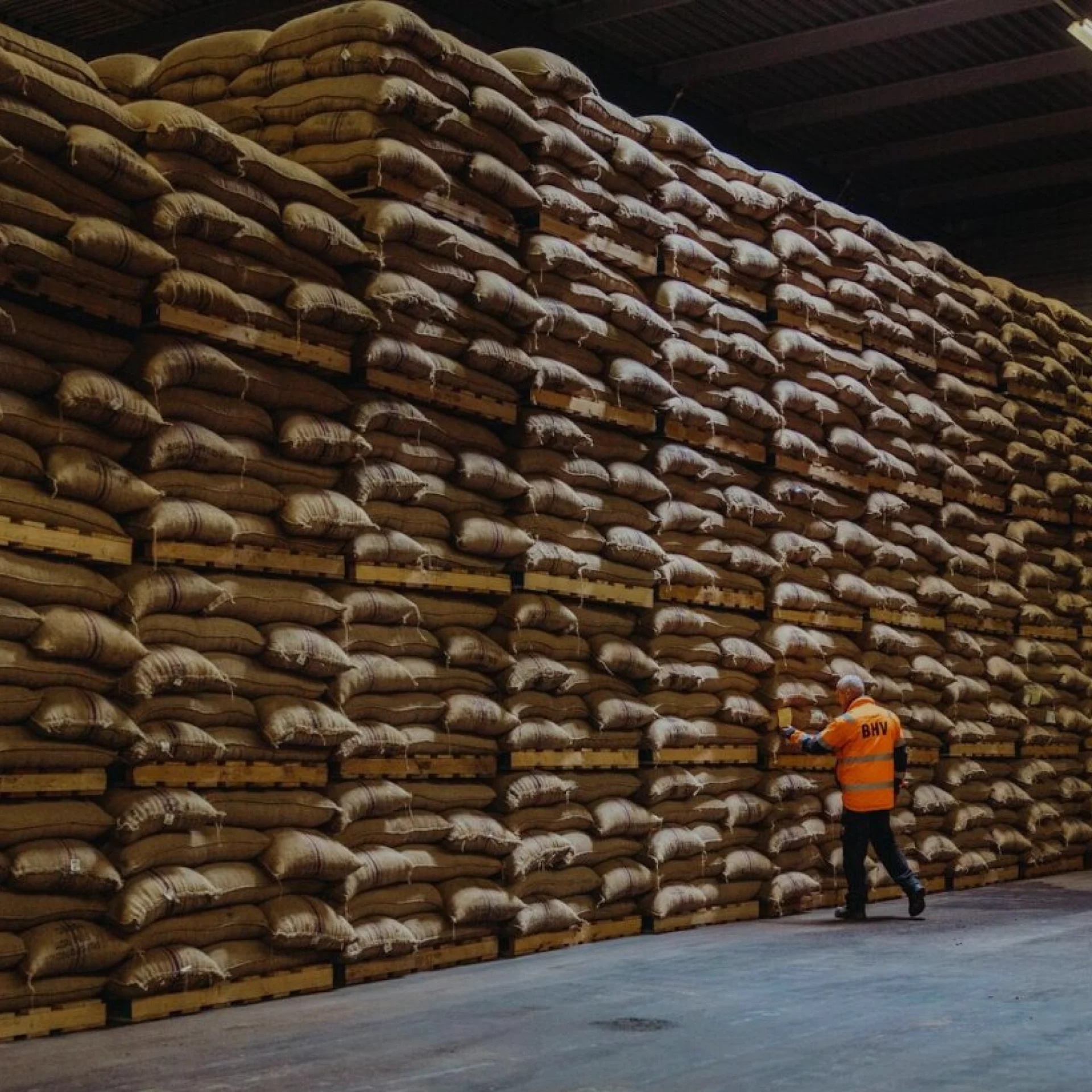 Gefüllte Säcke liegen übereinander gestapelt in einer Lagerhalle